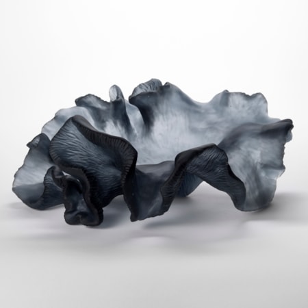 semi transparent dark grey undulating and rippling form with appearance of a piece of coral with fine ridged textures on the underside hand made from glass