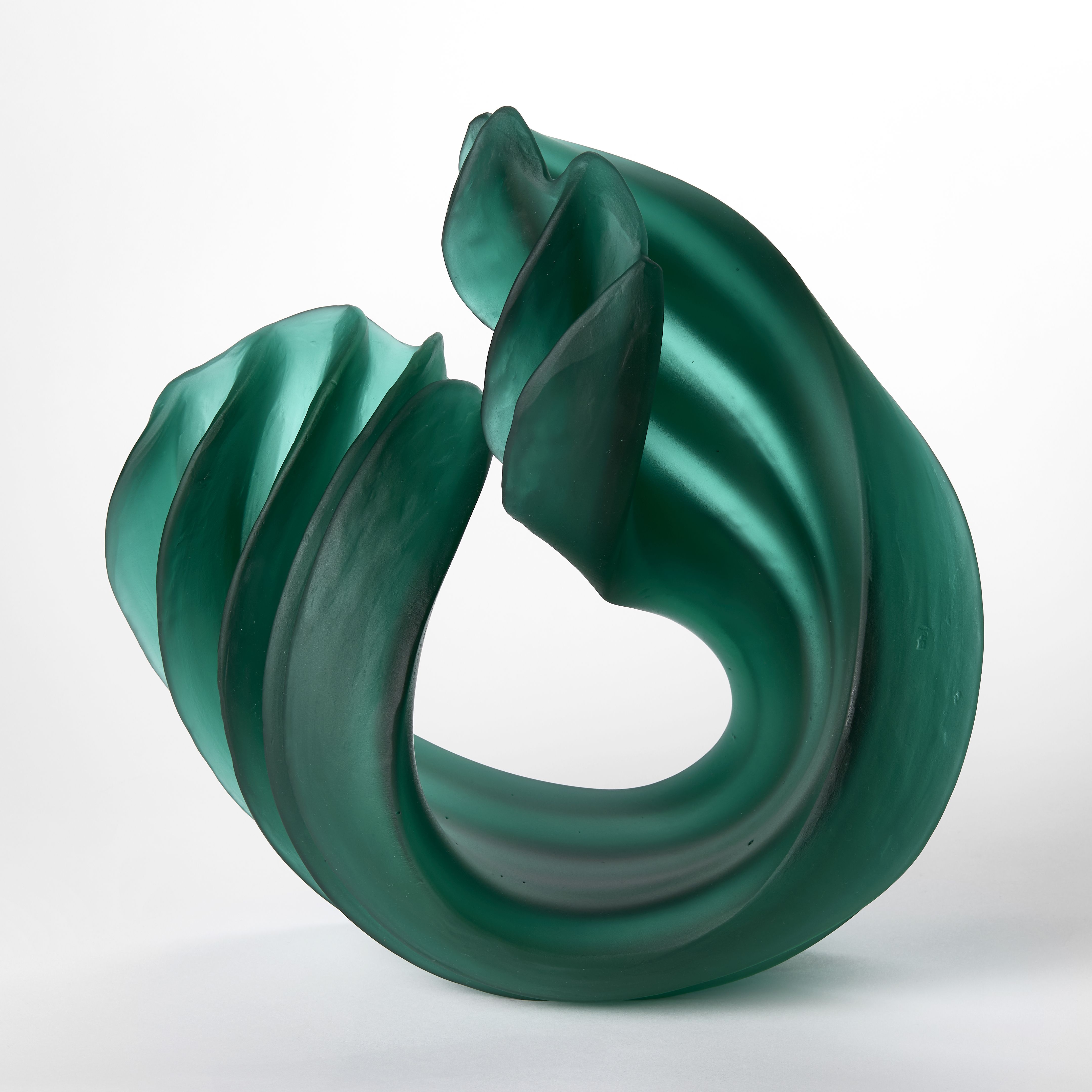 curling standing sculpture in semi transparent jade green with thick ridges and undulating edges hand made from glass