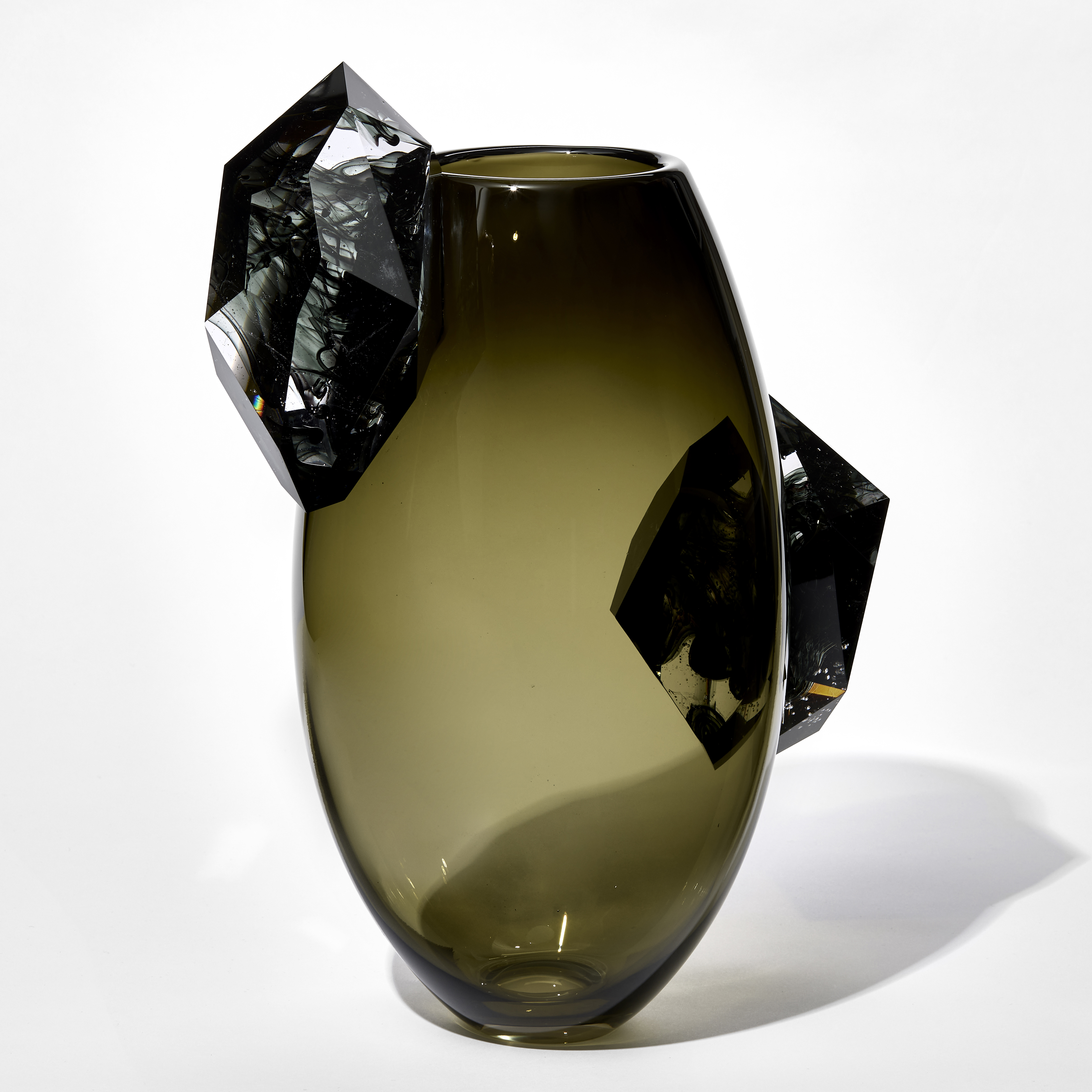 ovoid shaped transparent smokey olive vase with two large facetted crystals perched on either side one near the rim and the other on the opposite side half way down each clear but with swirling grey inky trails within hand blown and cut from glass
