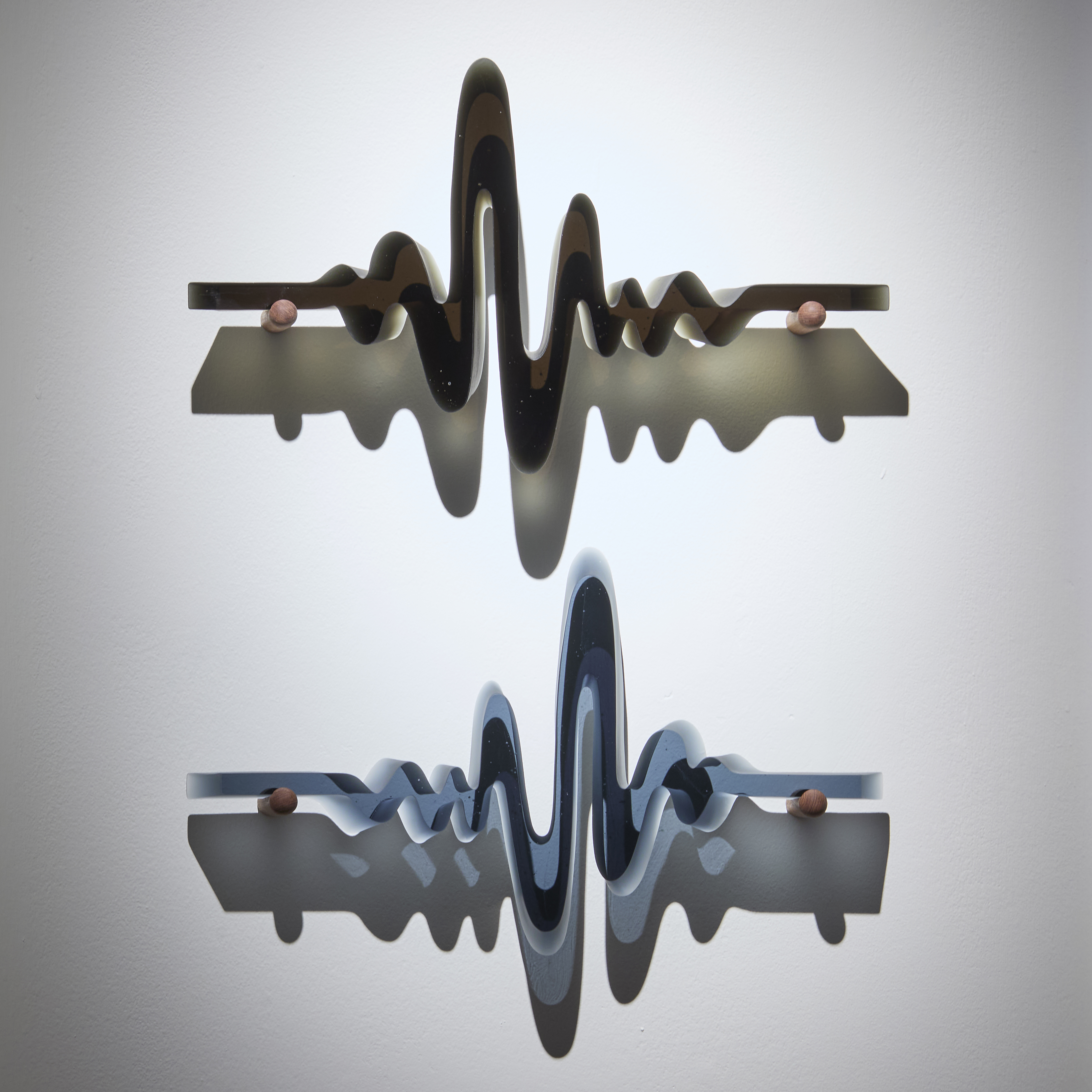 four semi transparent wall mounted sculptures in steel blue olive green amber and brown each with the appearance of a heart monitor read out following an undulating and dipping line made from cast glass with each resting on two teak fittings with all four positioned in an evenly spaced grid