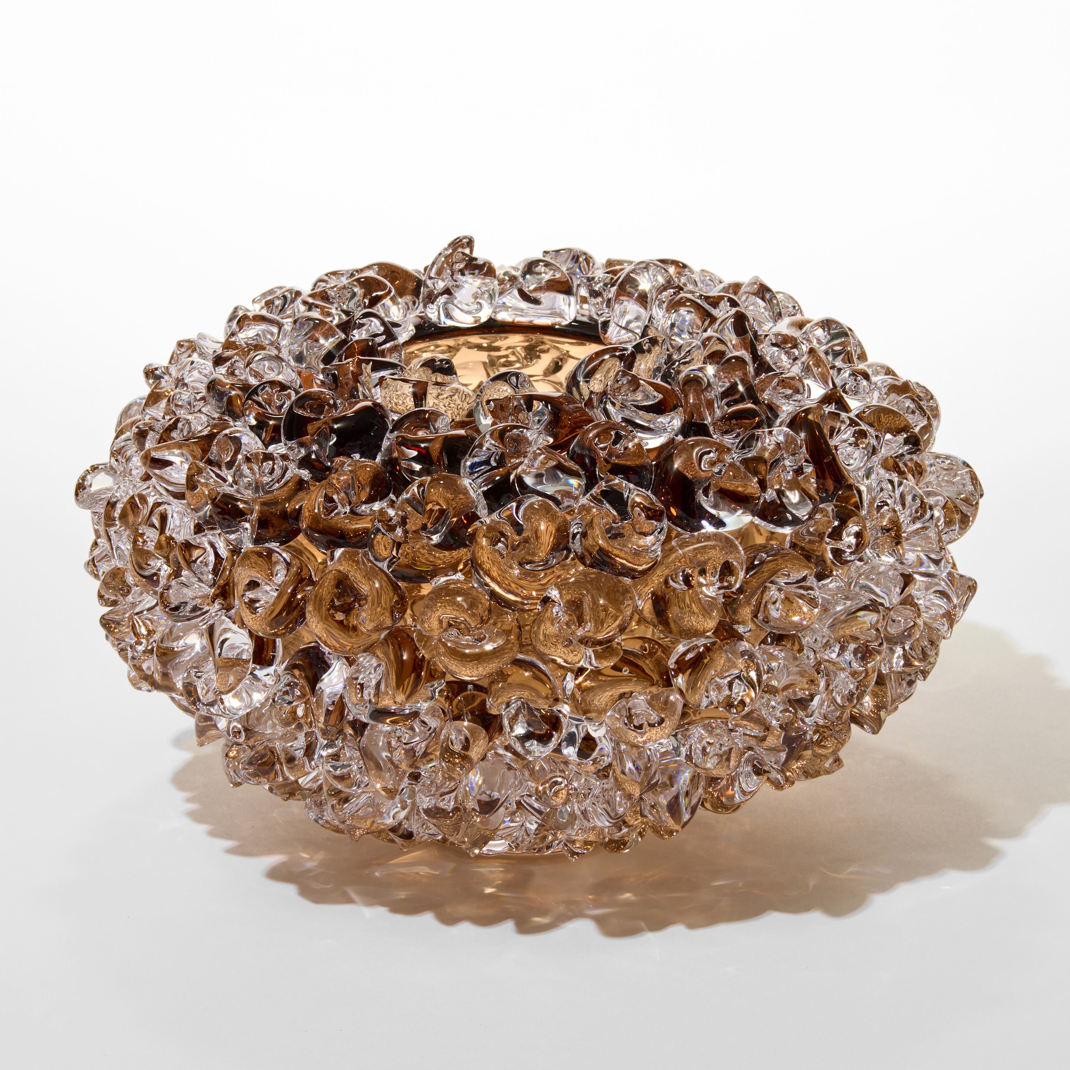 tea tobacco transparent low round vase with a small top opening and outer surface covered in twisted raised chunky dots and knots hand made from blown glass hand