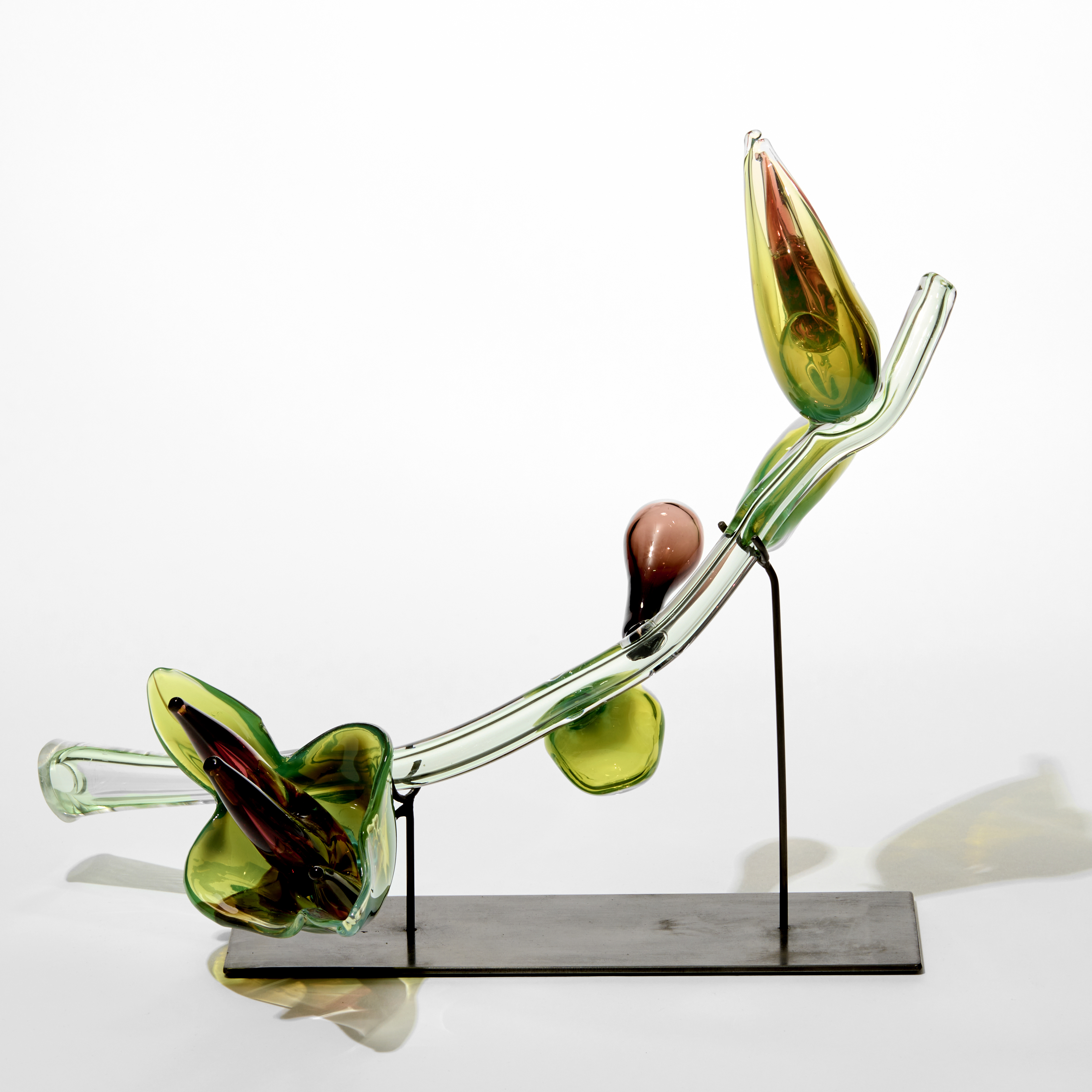 exotic plant inspired sculptural artwork with light green transparent organic curving stem with lime green leaves containing dark amber red finger shaped stamen hand made from glass