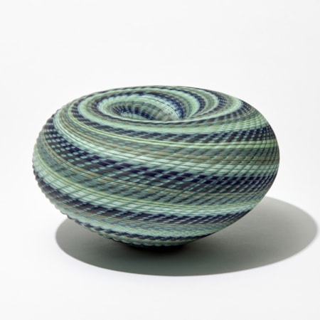 matt squat round donut shaped vessel with central descending inwards hole in coloured spiralling bands in celadon blue khaki and indigo handmade from blown and cut glass
