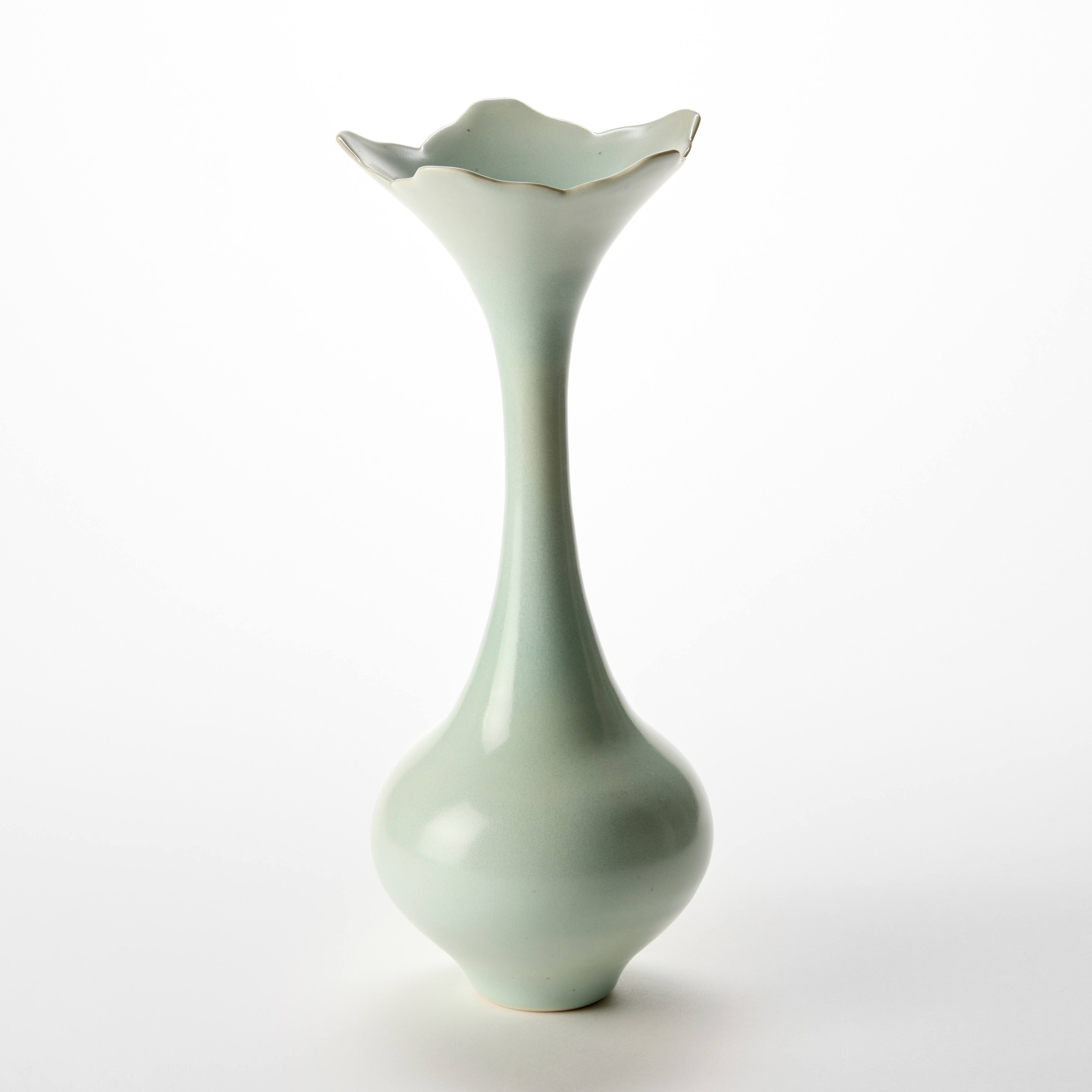 elegant vase with rounded base and long neck flaring to a five pointed petal shaped rim hand thrown from porcelain with a soft celadon glaze