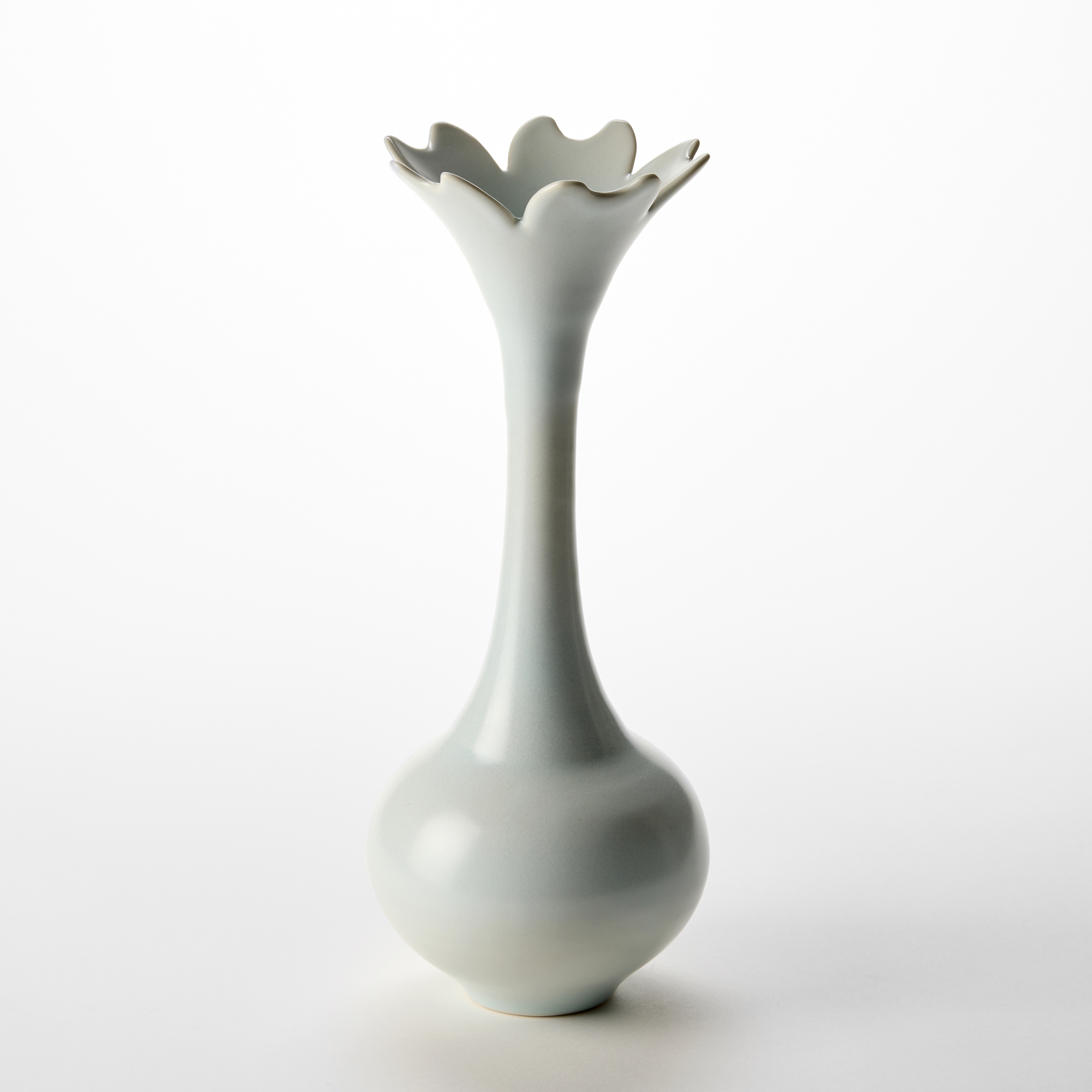 tall light turquoise vase with rounded base long thin neck flaring to a petal shaped undulating rim hand thrown from porcelain