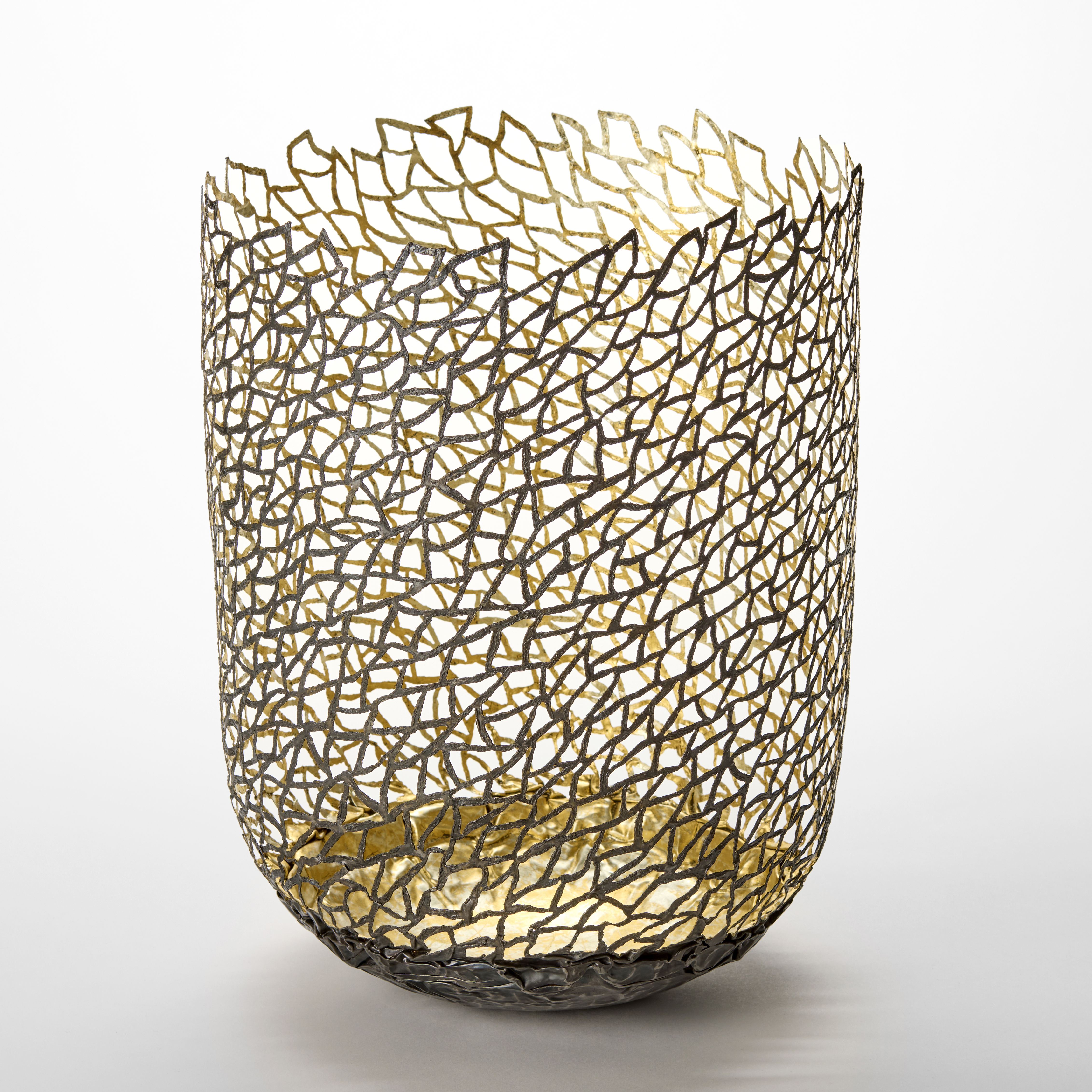 standing column shaped vessel with rounded base and organic lattice pattern perforating the entire side hand made from darkened steel and twenty four carat gold leaf 