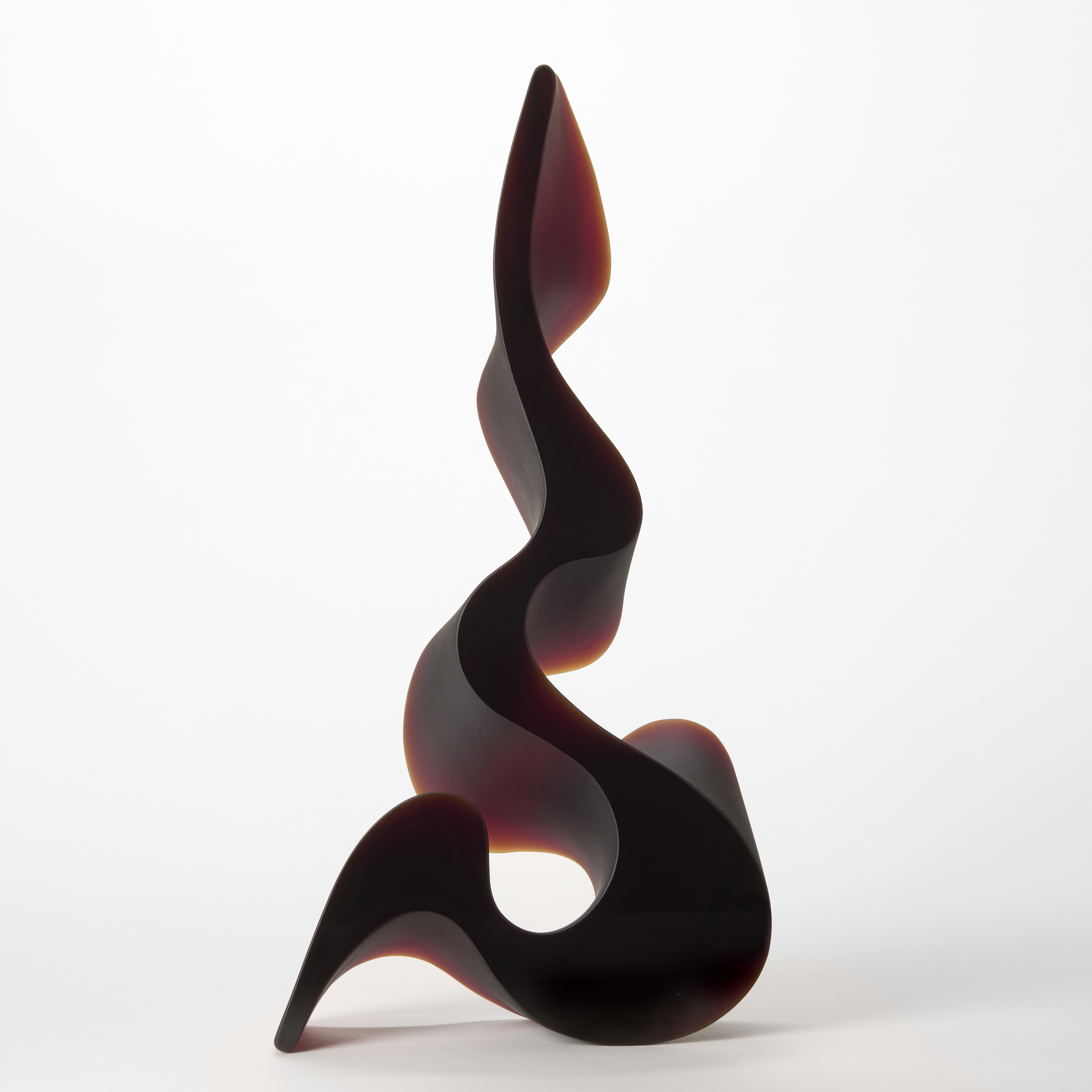tall curling opaque dark red fluid sculpture undulating back and forth narrower and narrower until reaching a final point hand made from cast glass