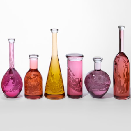 row of ten transparent different shaped bottles with wide bodies and narrow necks with caps on the top with each in red orange yellow peach or coral all containing an intricate lattice coral like structure hand made from glass