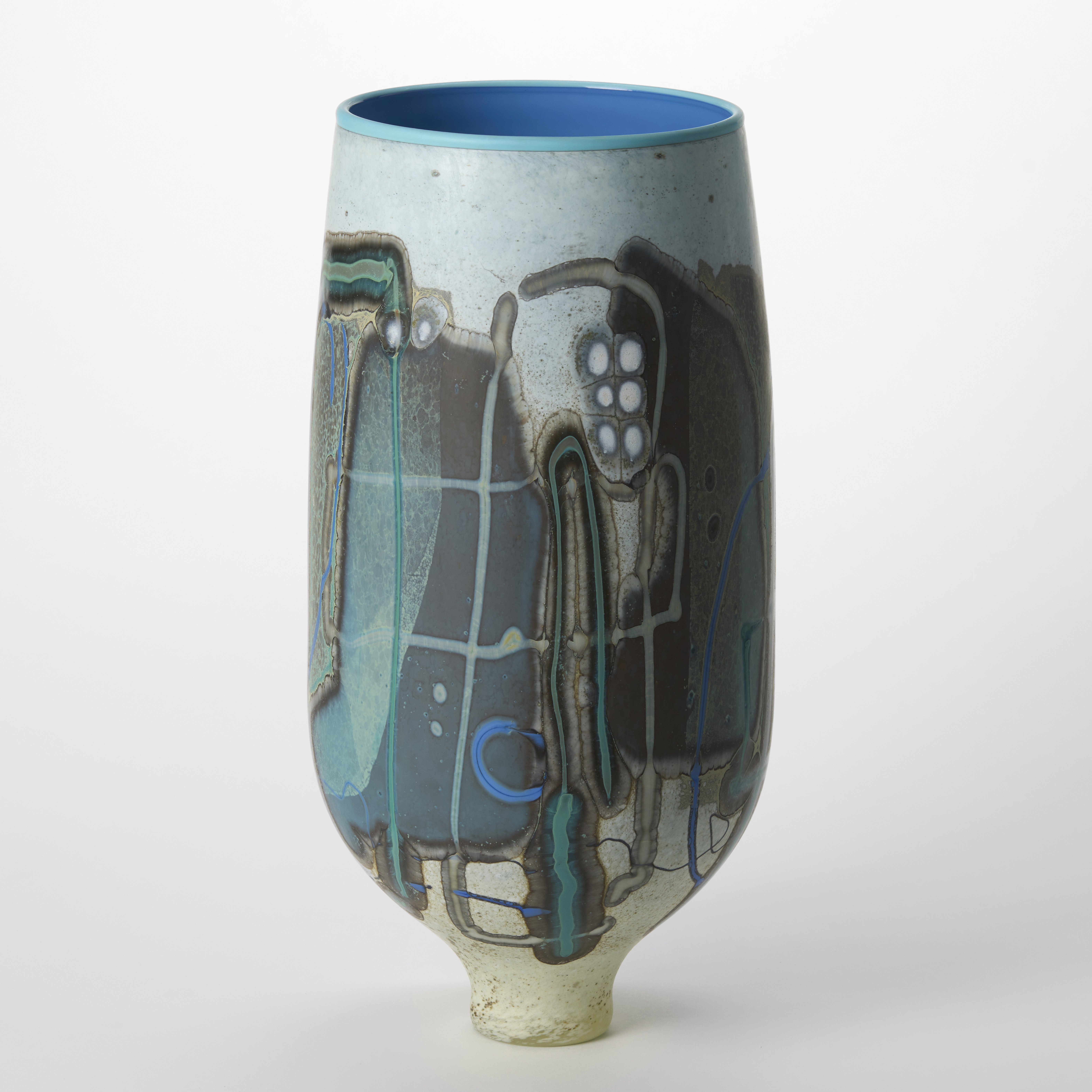 tall opaque mottled duck egg blue and white vase with an elegant narrow foot and surface decoration of abstract patterns in grey blue white teal ochre and brown and a glossy interior in rich mid blue hand blown from glass