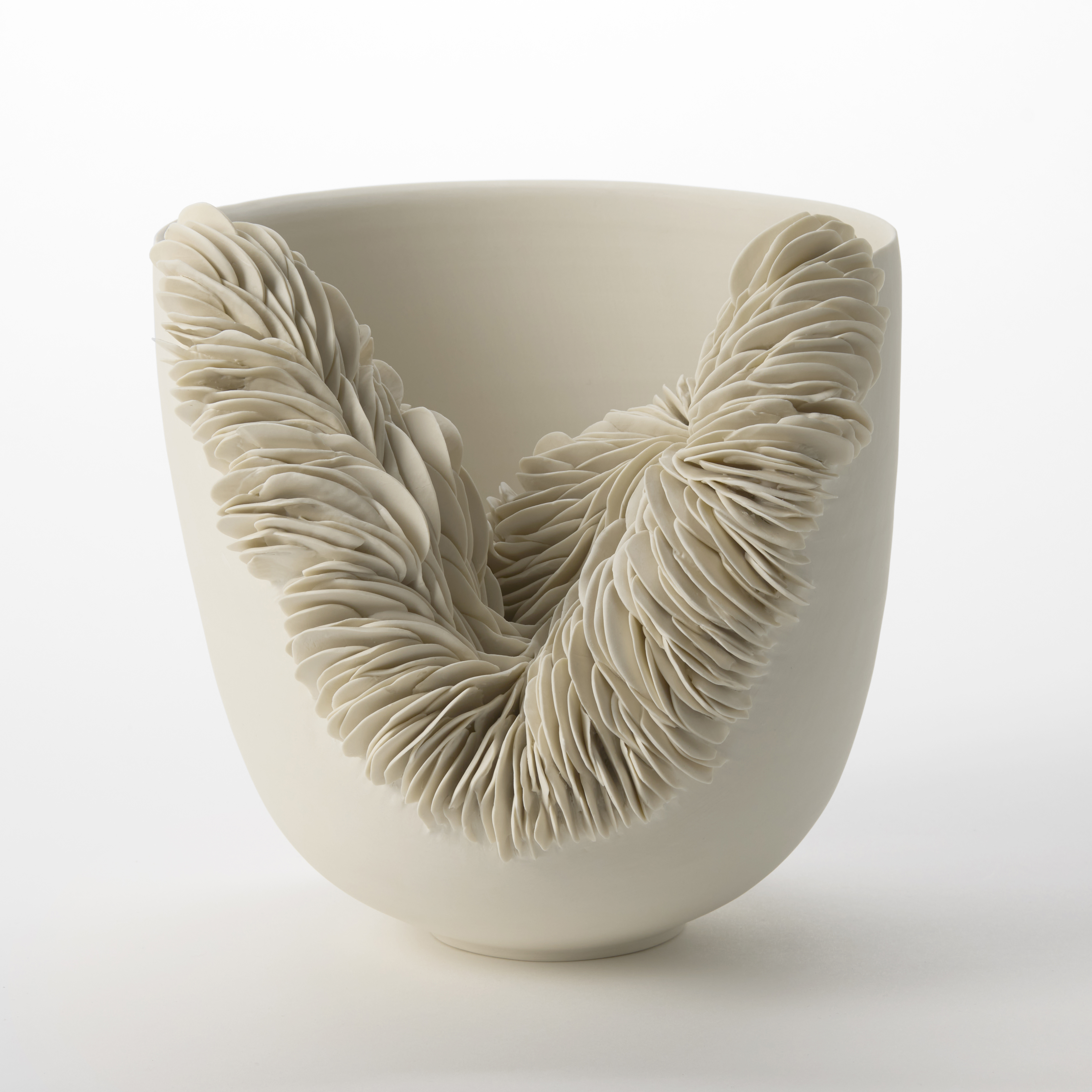 off white unglazed round porcelain flaring bowl with one third of the side cut away and with the revealed edge covered in stacked and layered shards hand made and thrown