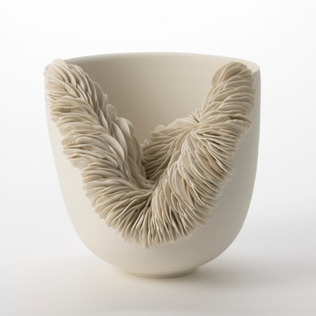 off white unglazed round porcelain flaring bowl with one third of the side cut away and with the revealed edge covered in stacked and layered shards hand made and thrown