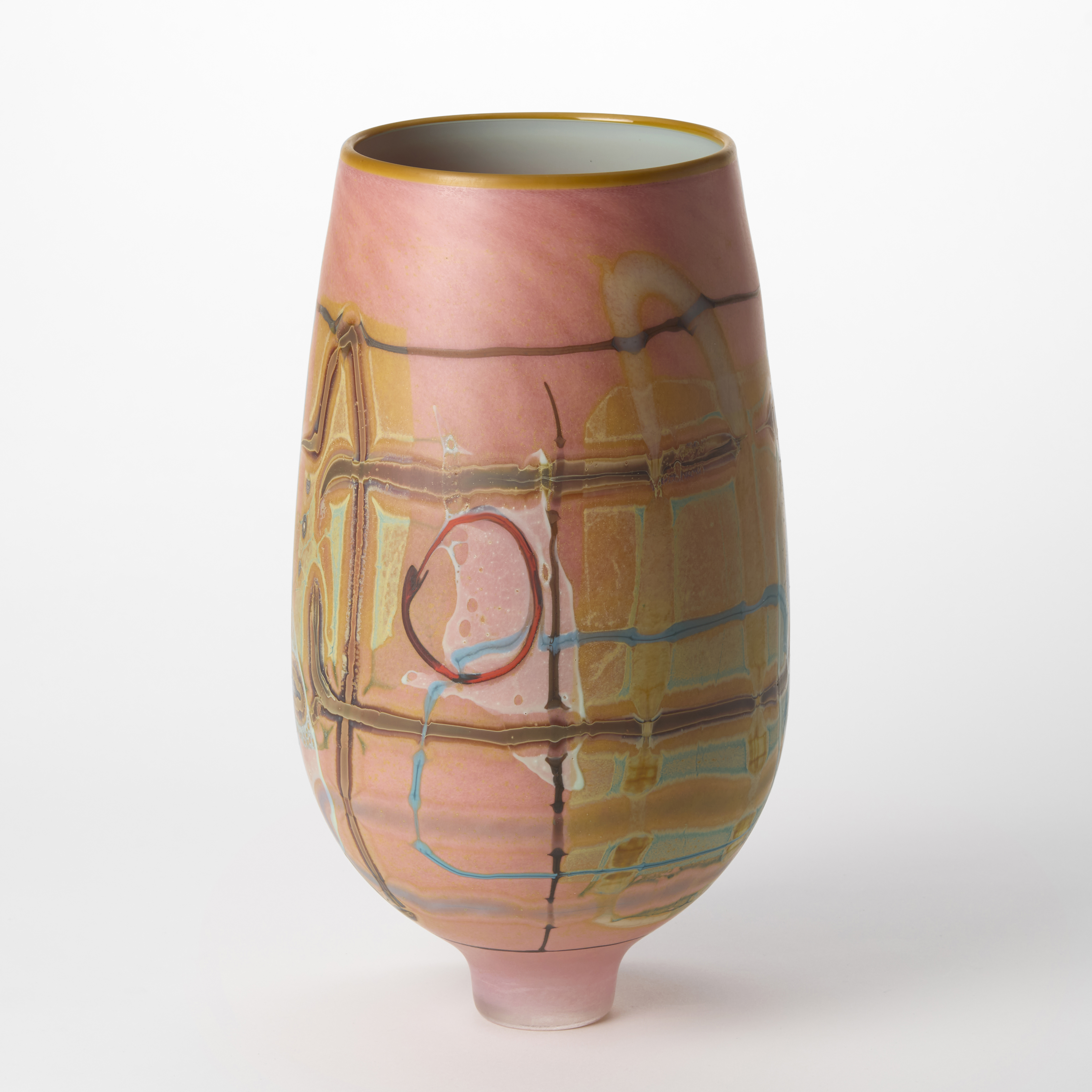 opaque flamingo pink tall vase perched on a narrow elegant foot with the exterior covered in abstract patterns in red grey ochre yellow and turquoise with a glossy interior in celadon hand blown from glass