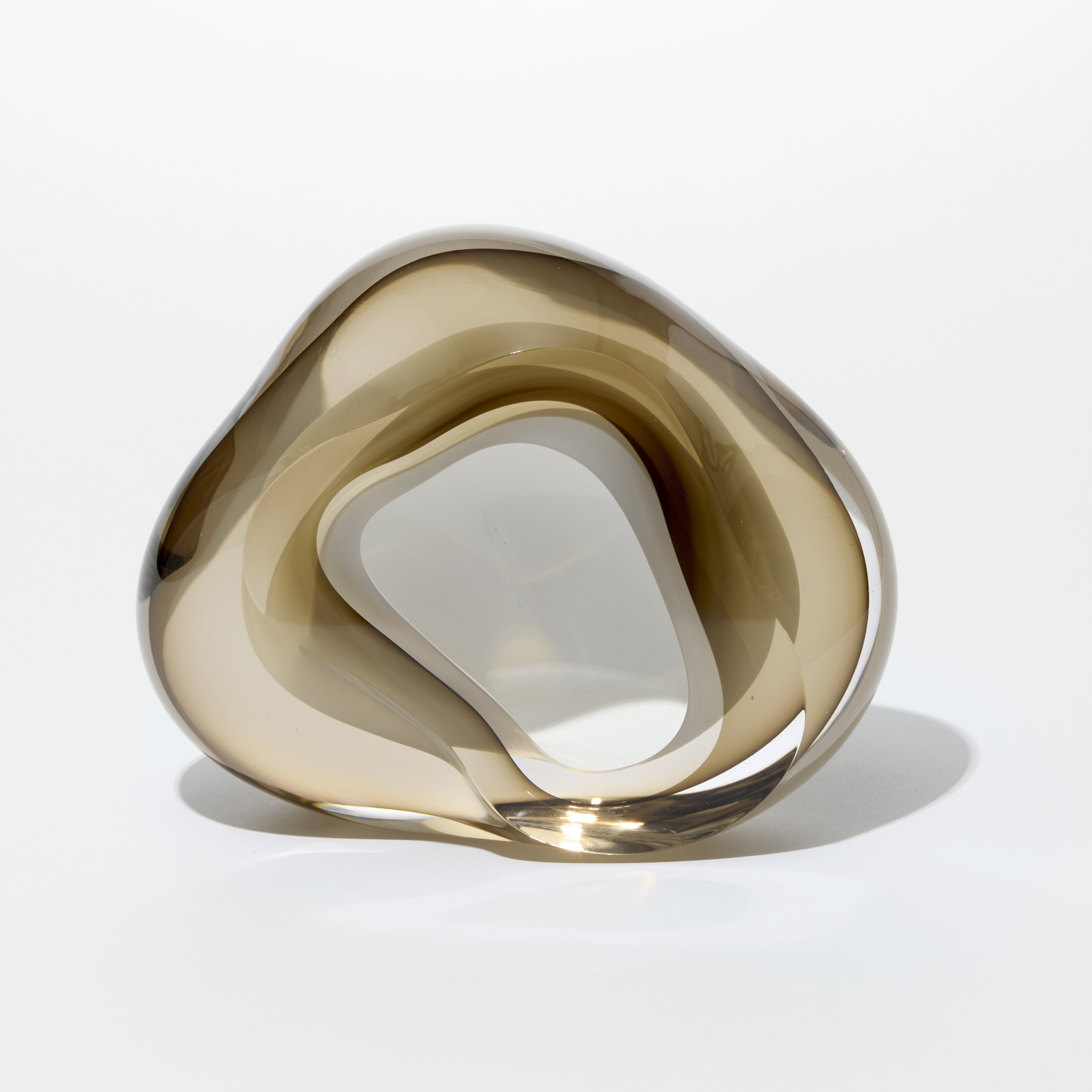 soft rounded transparent and light bronze taupe amorphic geode rock inspired artwork with fluid lines and interior white lined cavity hand made from glass