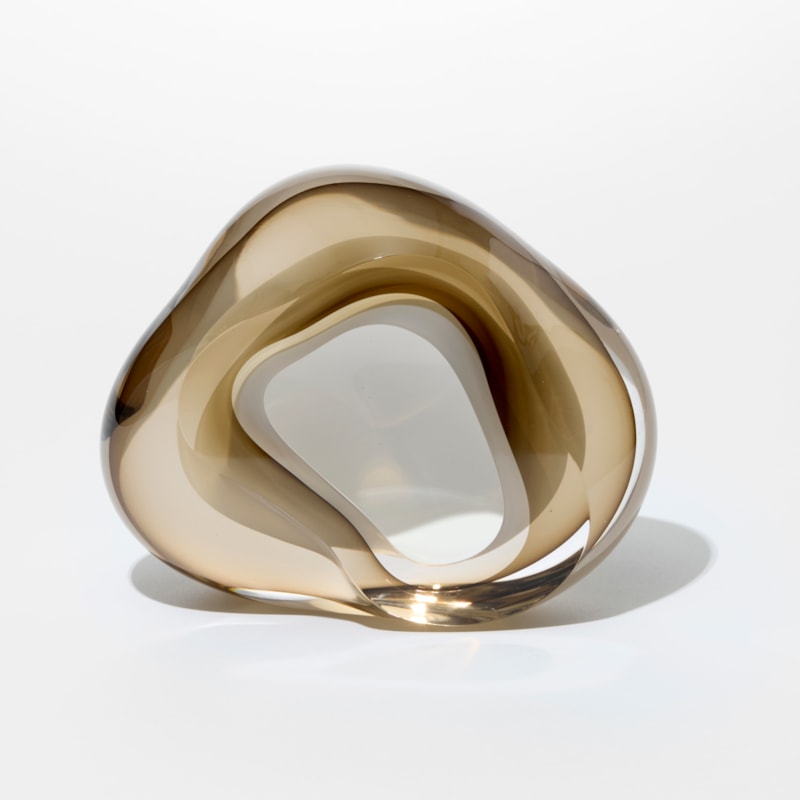 soft rounded transparent and light bronze taupe amorphic geode rock inspired artwork with fluid lines and interior white lined cavity hand made from glass