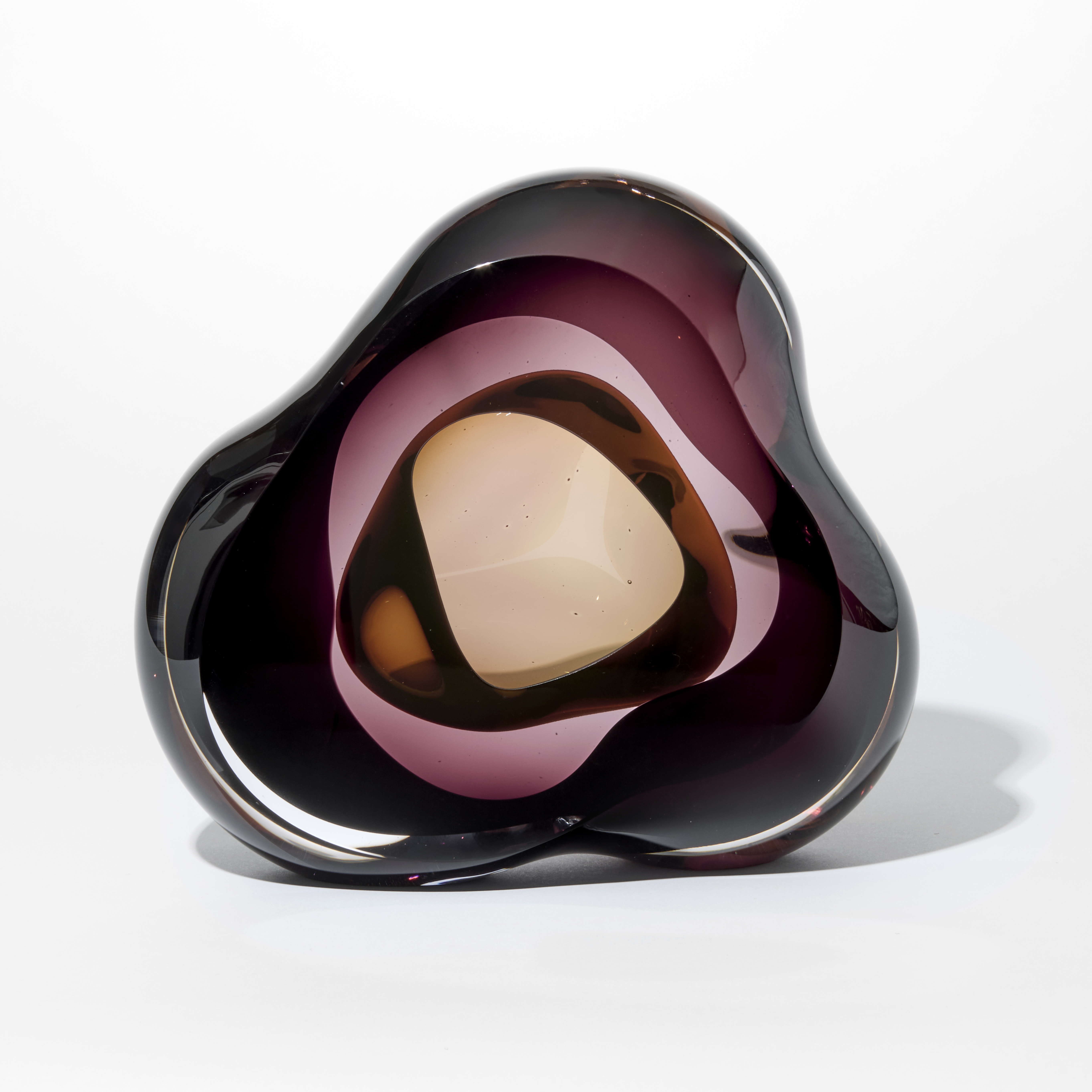 glossy transparent aubergine and brown fluid pebble with three rounded corners and interior rounded cavity hand made from glass