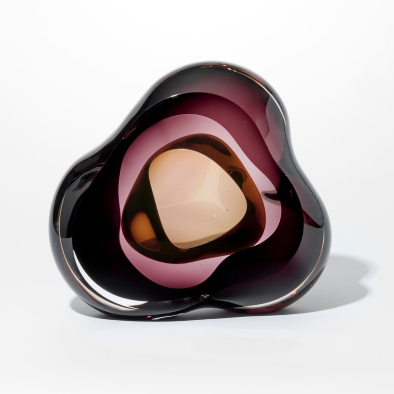 glossy transparent aubergine and brown fluid pebble with three rounded corners and interior rounded cavity hand made from glass