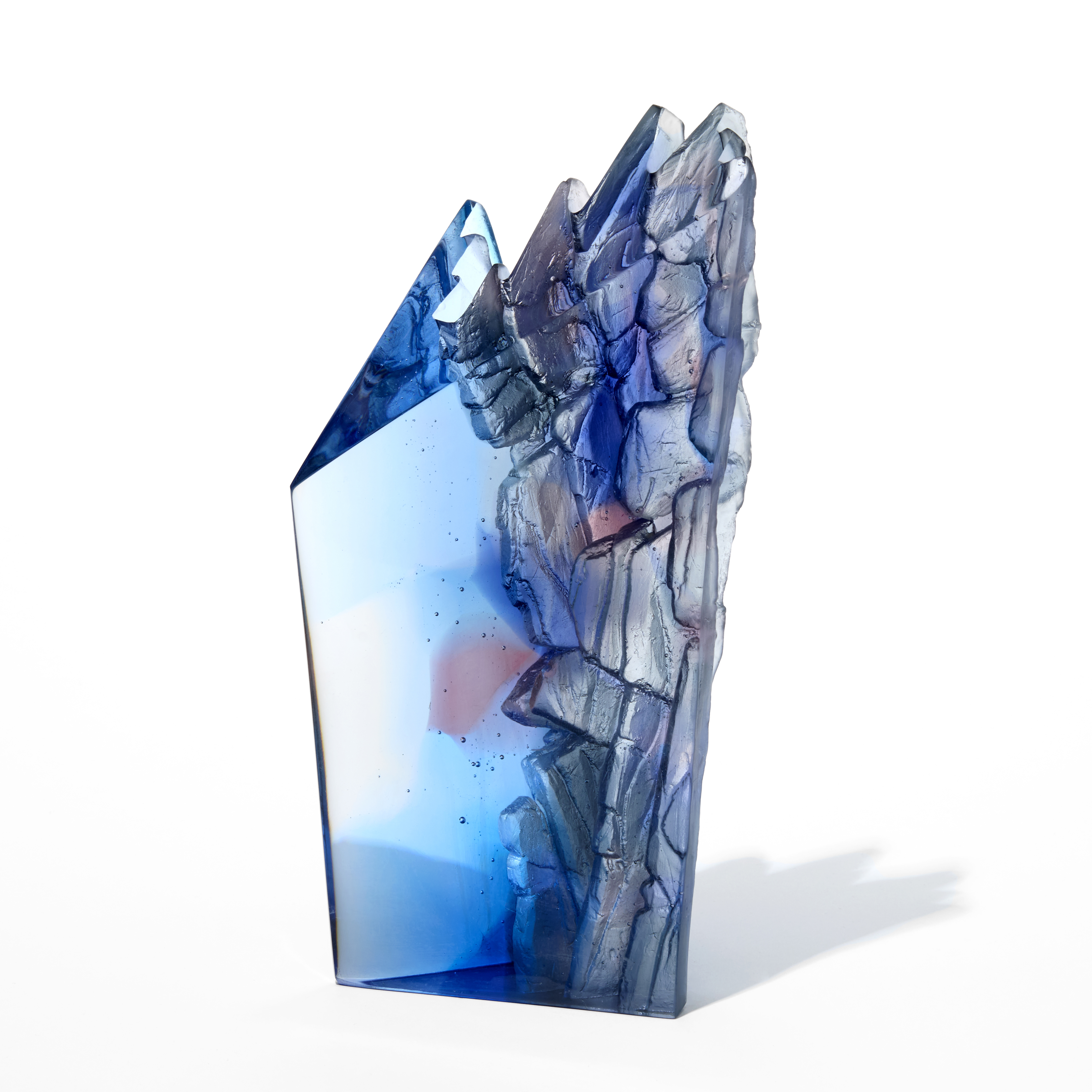 standing transparent blue with specs of deep pink rock face inspired sculpture with two two sides polished flat and two inverted sides with a craggy rough texture hand made from cast glass