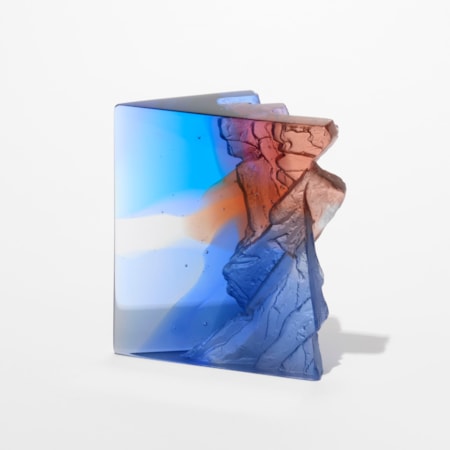 transparent blue clear grey and sienna sculpture resembling a section of a cliff face with an angular form and two shiny flat sides with one side covered in craggy texture hand made from glass