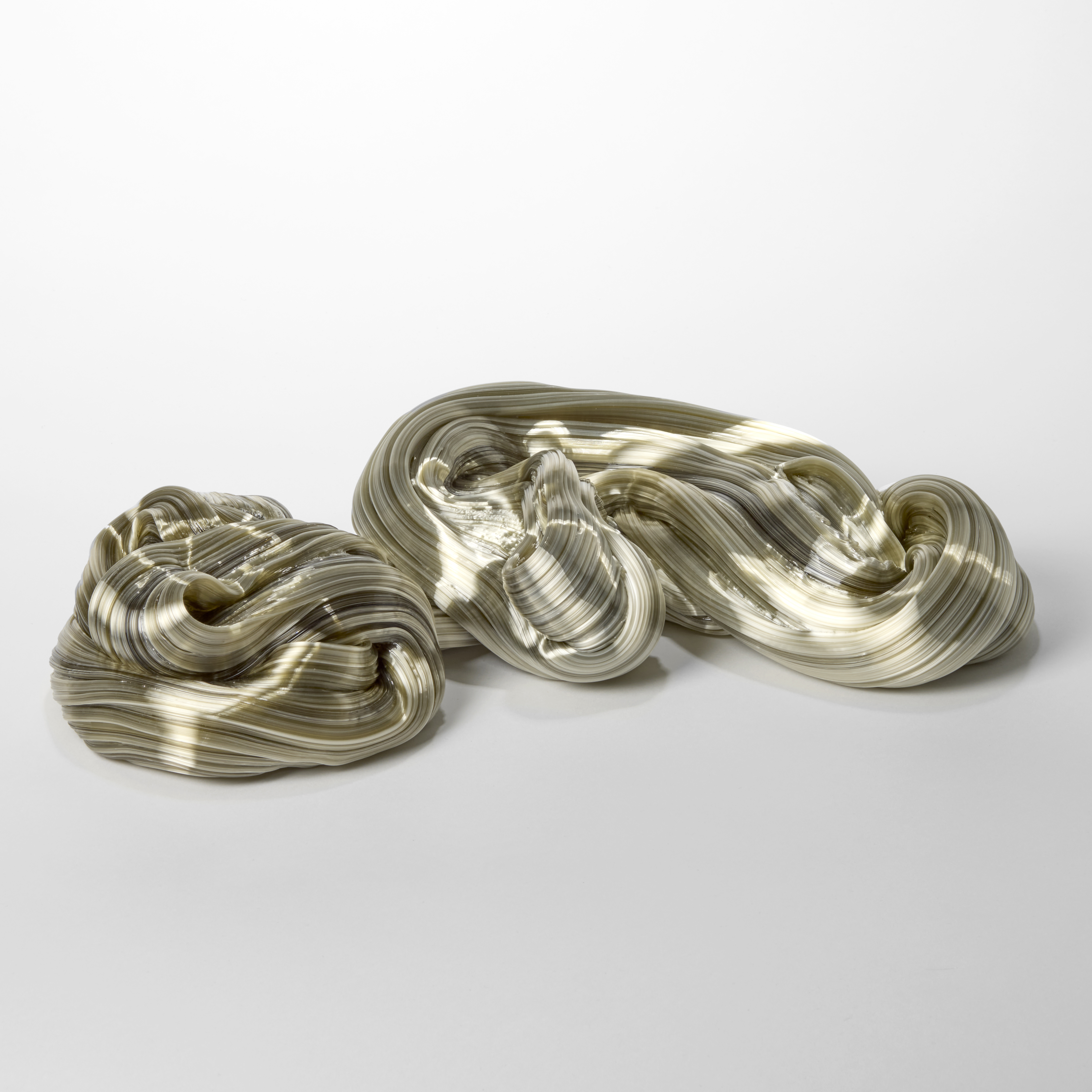 low winding undulating finely ridged organic trailing mass with the appearance of silk cord with a satin shiny finish in soft olive green hand made from glass