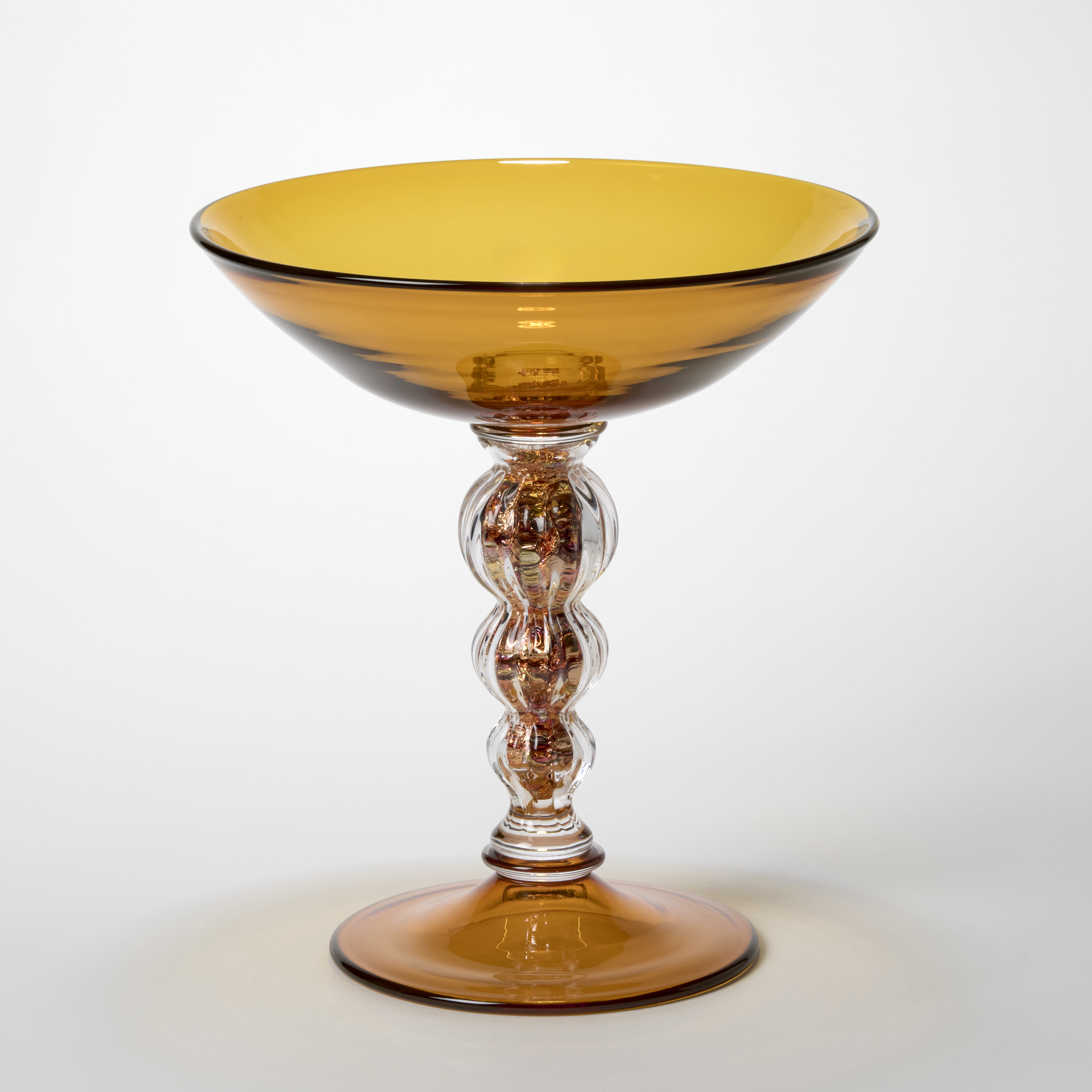 rich transparent tall amber centrepiece with undulating ridged stem filled with silver and brass leaf hand blown from glass employing venetian techniques