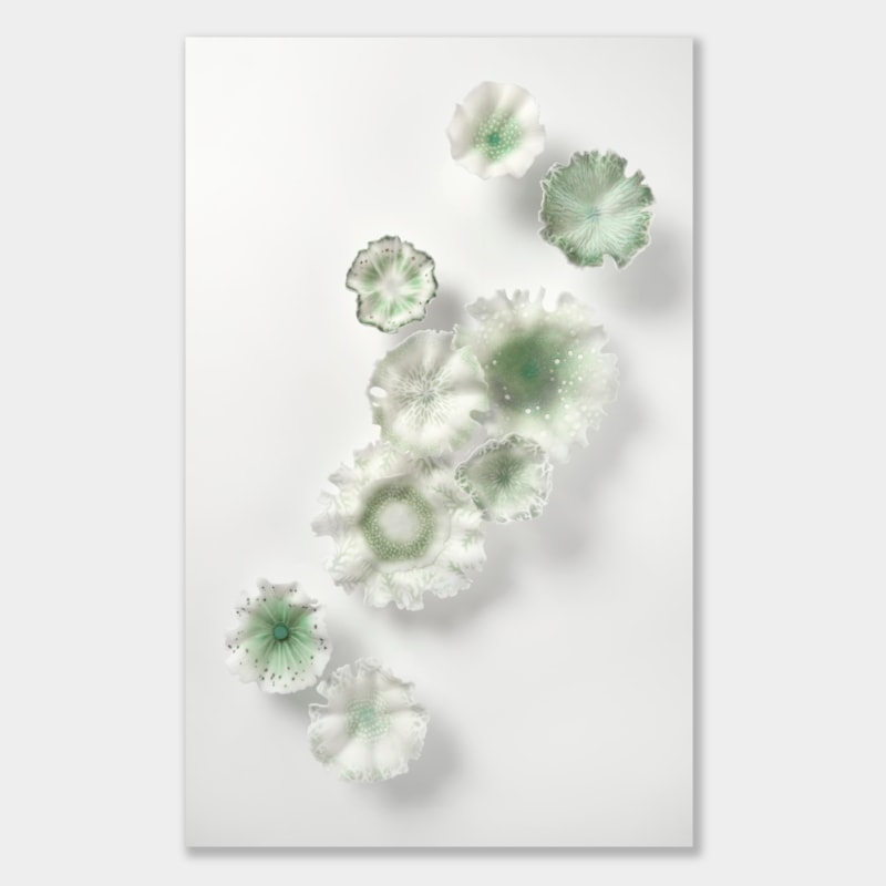nine soft feather edged organic wall mounted floral shapes in white and muted green with delicate surface patterns and decoration hand made from glass