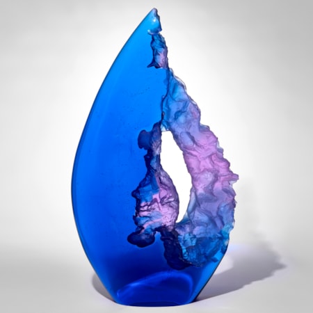 tall pointy transparent teardrop shaped sculpture in electric blue and purple with one side smooth and shiny and the other cut with rock like texture leaving a central opening through the piece hand made from cast glass