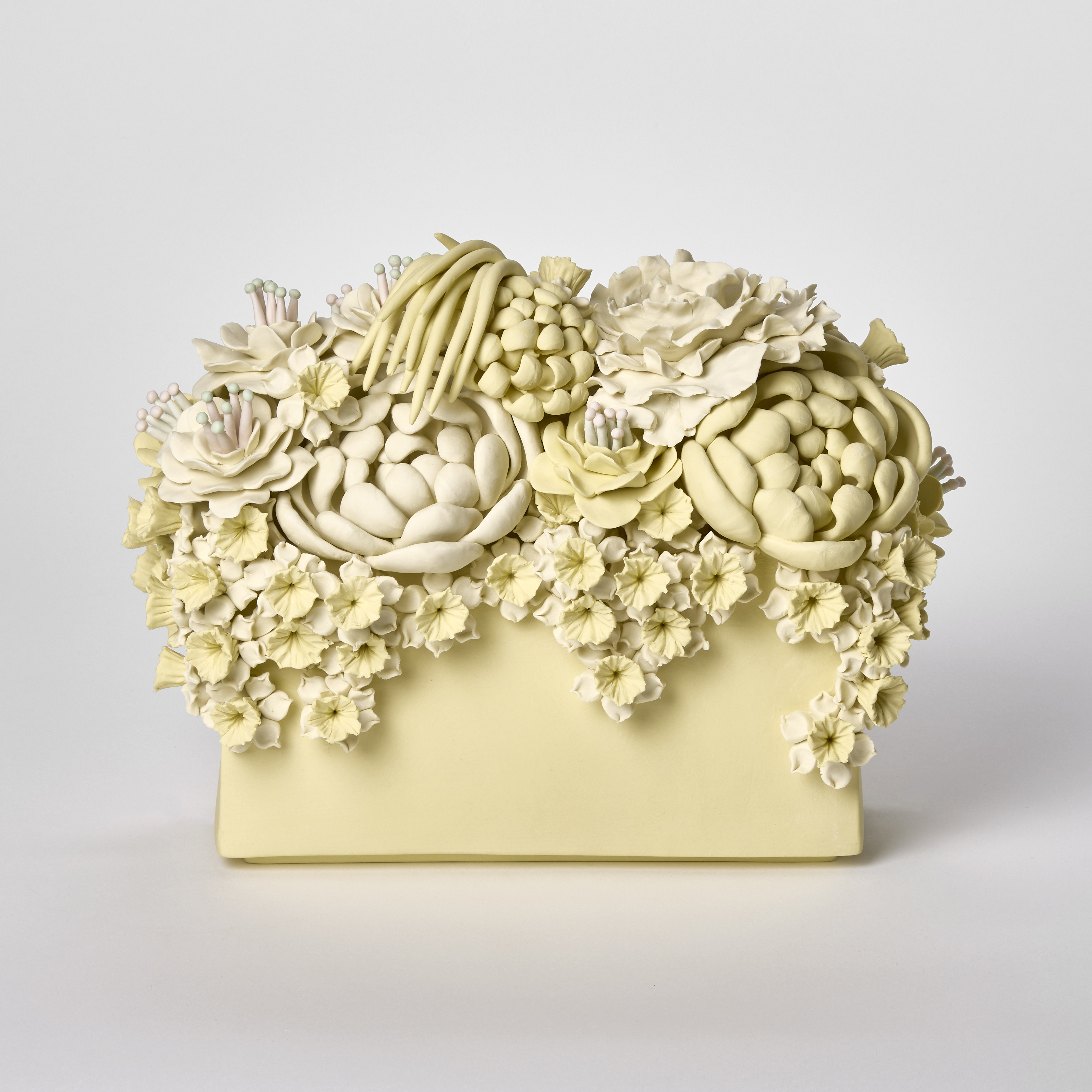 low matt yellow block with the top covered in various flowers and blooms that also cascade down the sides hand made from porcelain
