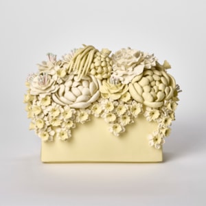 low matt yellow block with the top covered in various flowers and blooms that also cascade down the sides hand made from porcelain