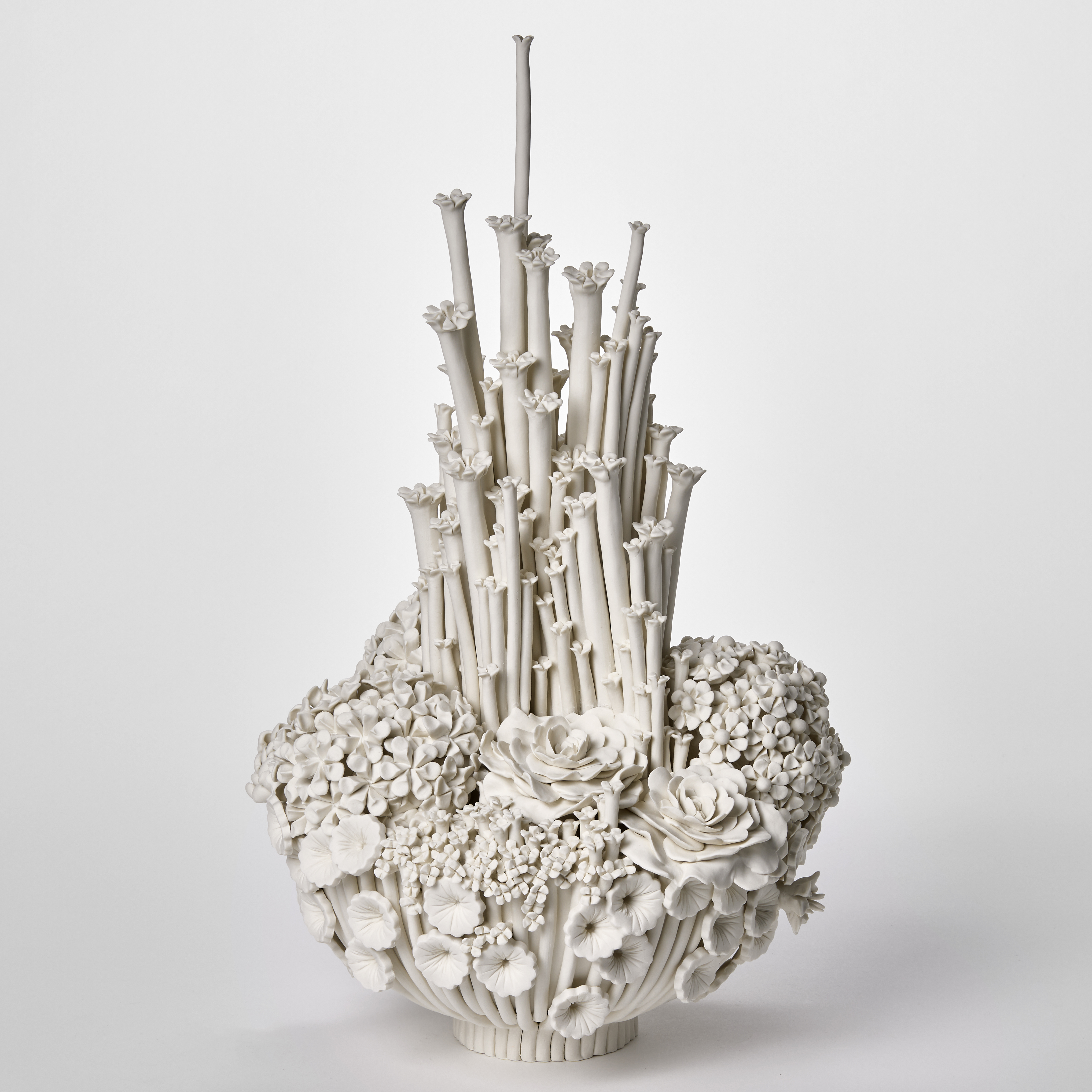 tall bottom heavy round white floral display with various flowers and blooms clustered together and very tall central stems with tiny flowers on top hand made from porcelain