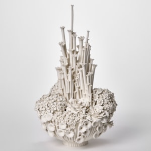 tall bottom heavy round white floral display with various flowers and blooms clustered together and very tall central stems with tiny flowers on top hand made from porcelain