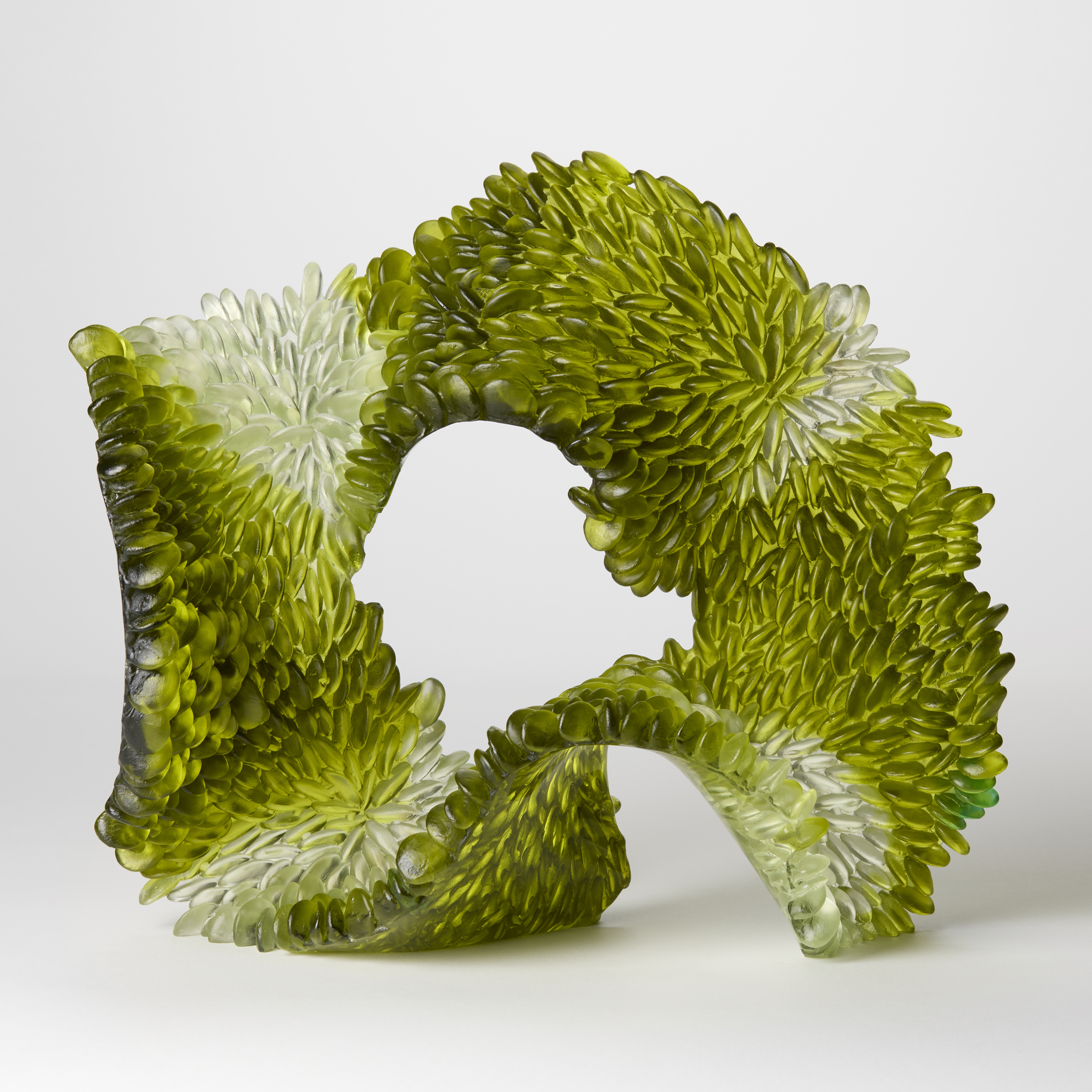 standing opaque looping soft oval form in olive green and soft grey with the facing surface covered in tessellated scales hand made from glass