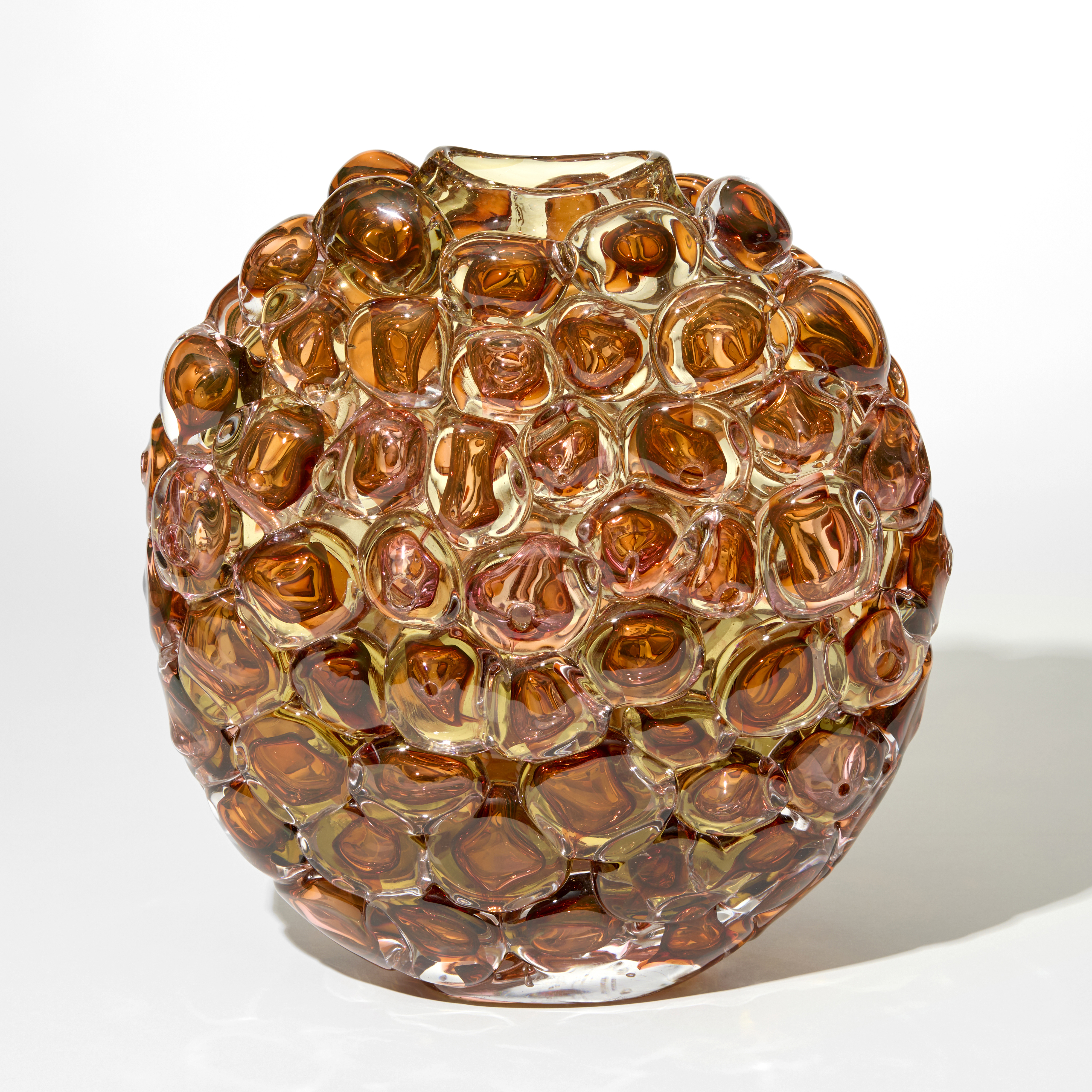 transparent amber gold and coral vase with an oval profile and outer surface covered in large oversized squashed bubbles hand blown from glass