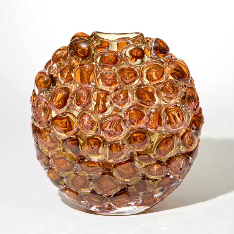 transparent amber gold and coral vase with an oval profile and outer surface covered in large oversized squashed bubbles hand blown from glass