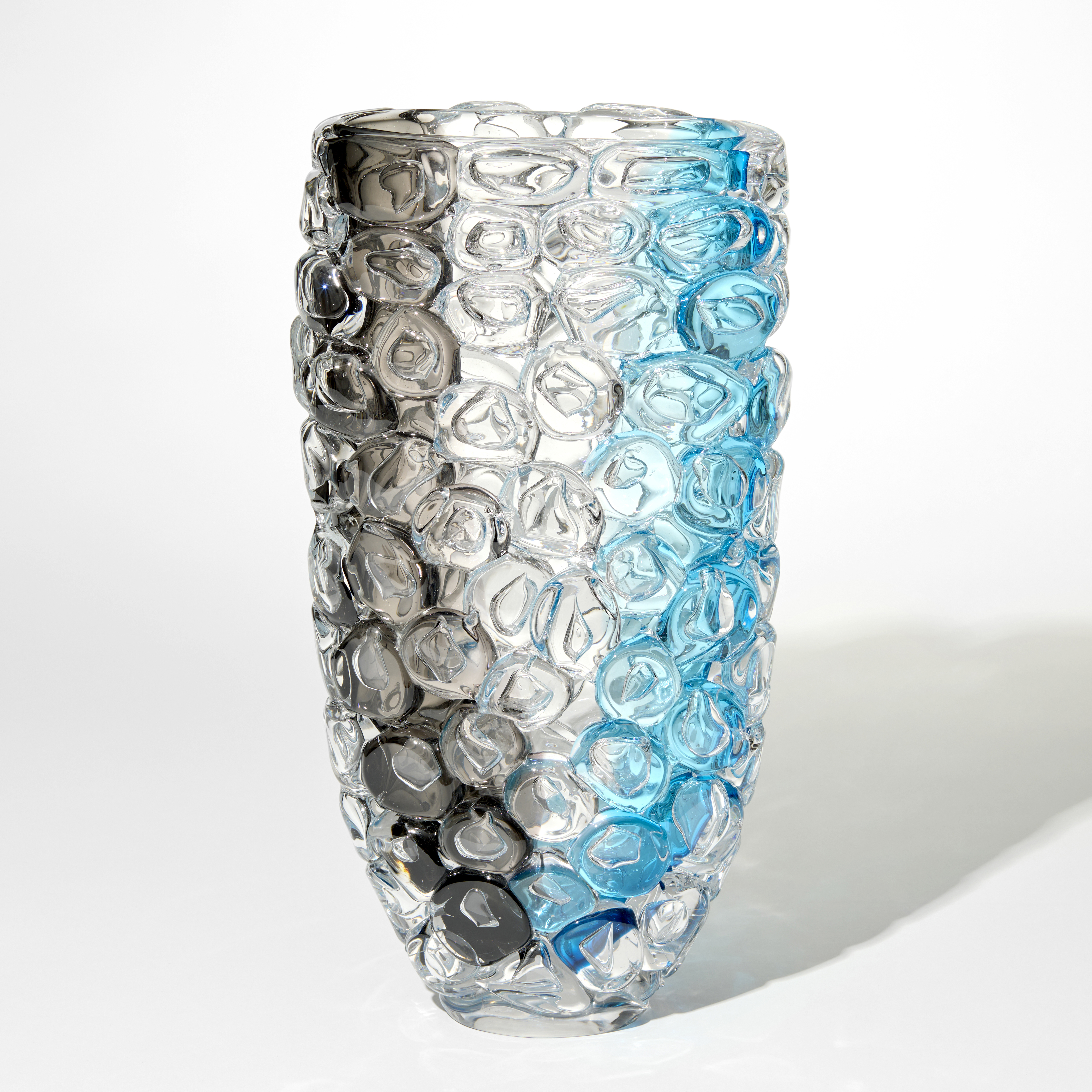 tall transparent vase with a band of grey on one side and bright aquamarine on the other with the complete outer surface covered in large oversized bubbles like bubble wrap hand made from glass