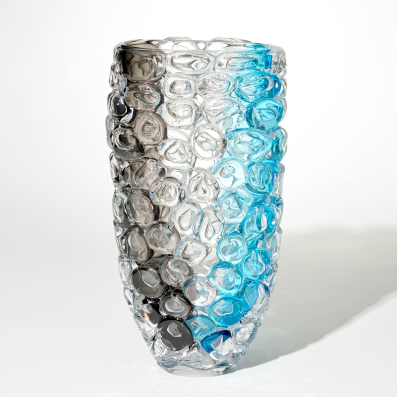 tall transparent vase with a band of grey on one side and bright aquamarine on the other with the complete outer surface covered in large oversized bubbles like bubble wrap hand made from glass