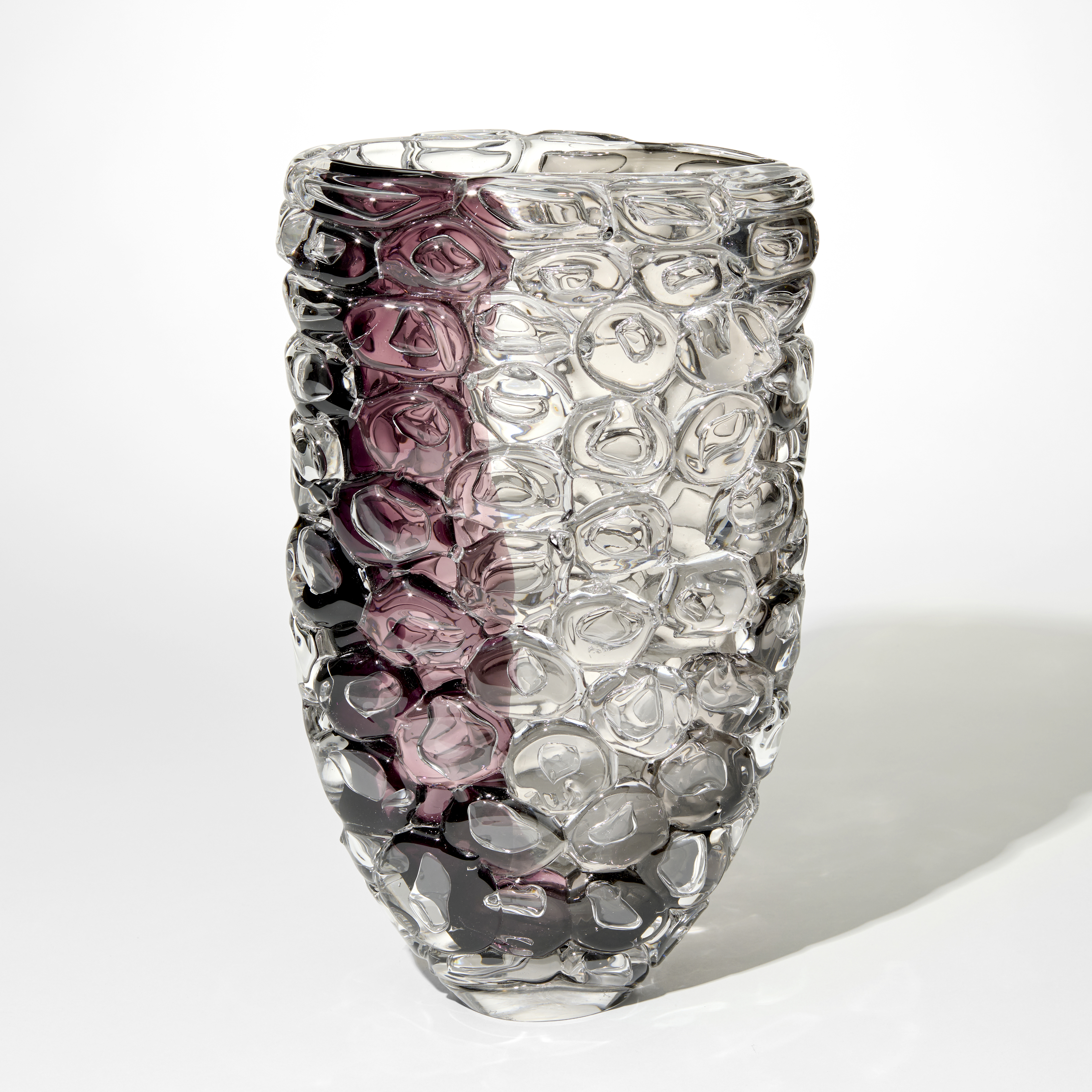 tall widening transparent vase with one size with a band of aubergine and the other grey with the outer surface covered in oversized squashed bubbles hand made from glass