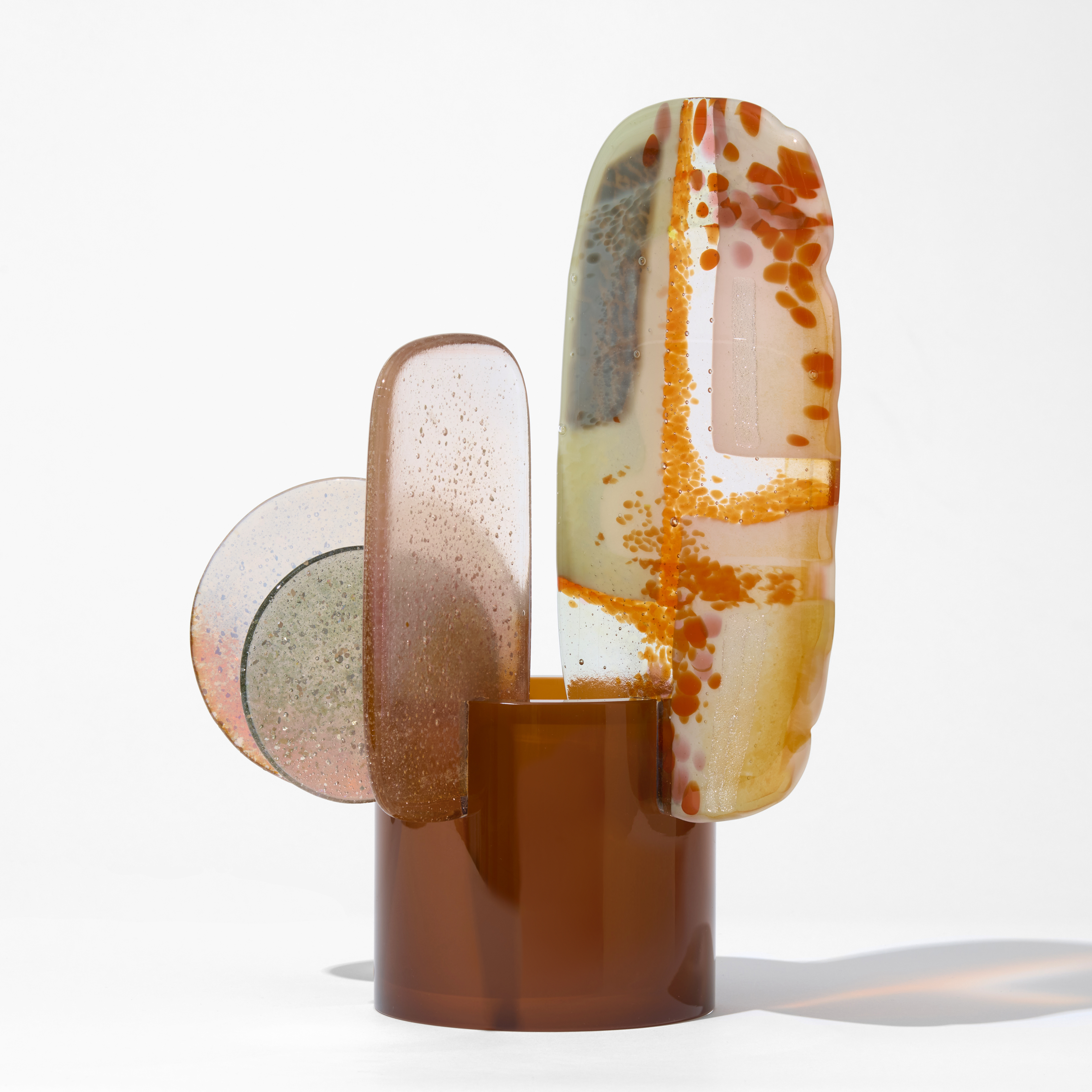 short glossy opaque sienna round tube with two round and three long  transparent fins perched on the top edge each with abstract patterns in grey pink orange and red hand made from blown and fused glass