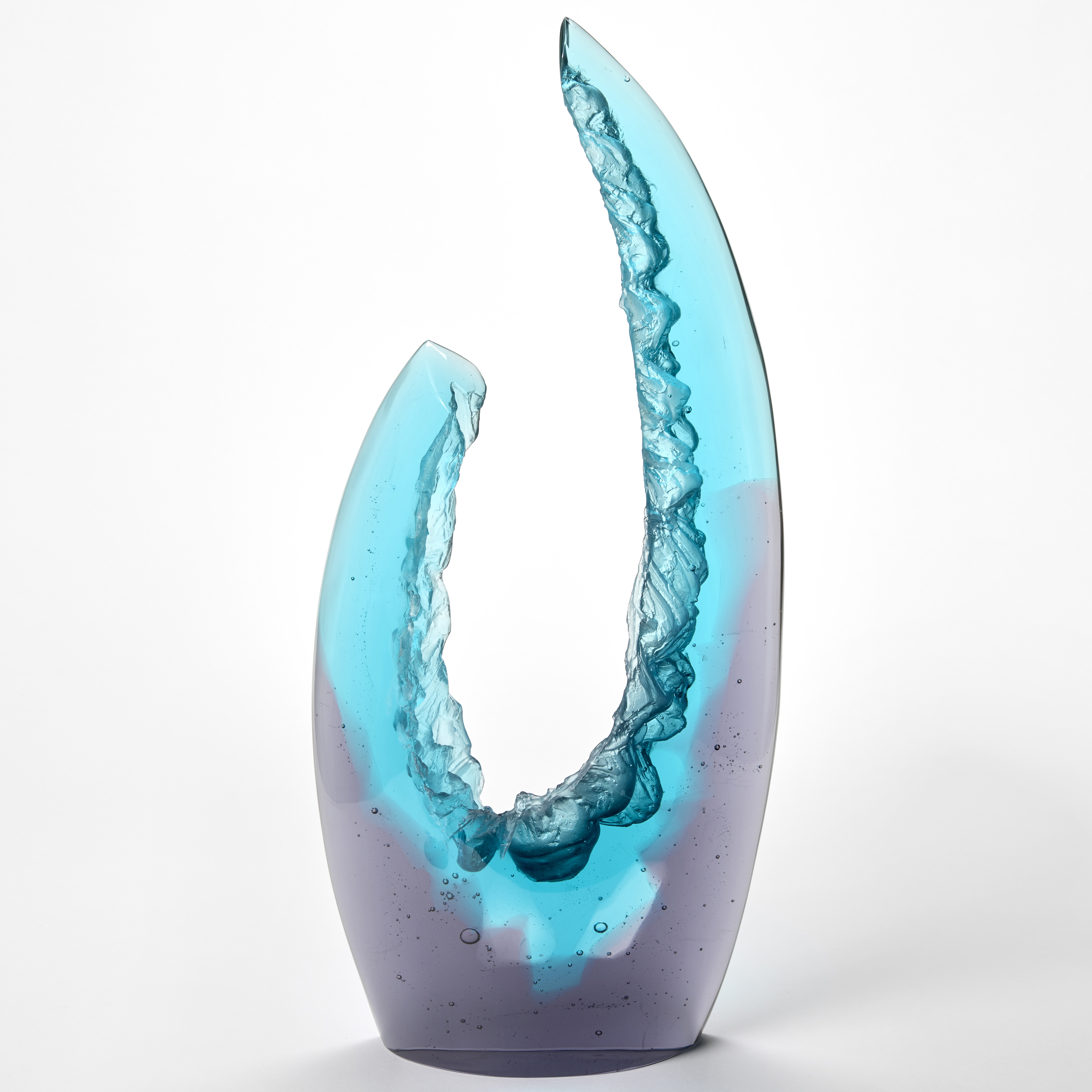 tall abstract glass sculpture with a gradient from deep purple at the base to bright turquoise at the top with the form reaching and curving upwards into two asymmetrical points  creating an open crescent like structure and the interior edges with rock like surface texture hand made from cast glass