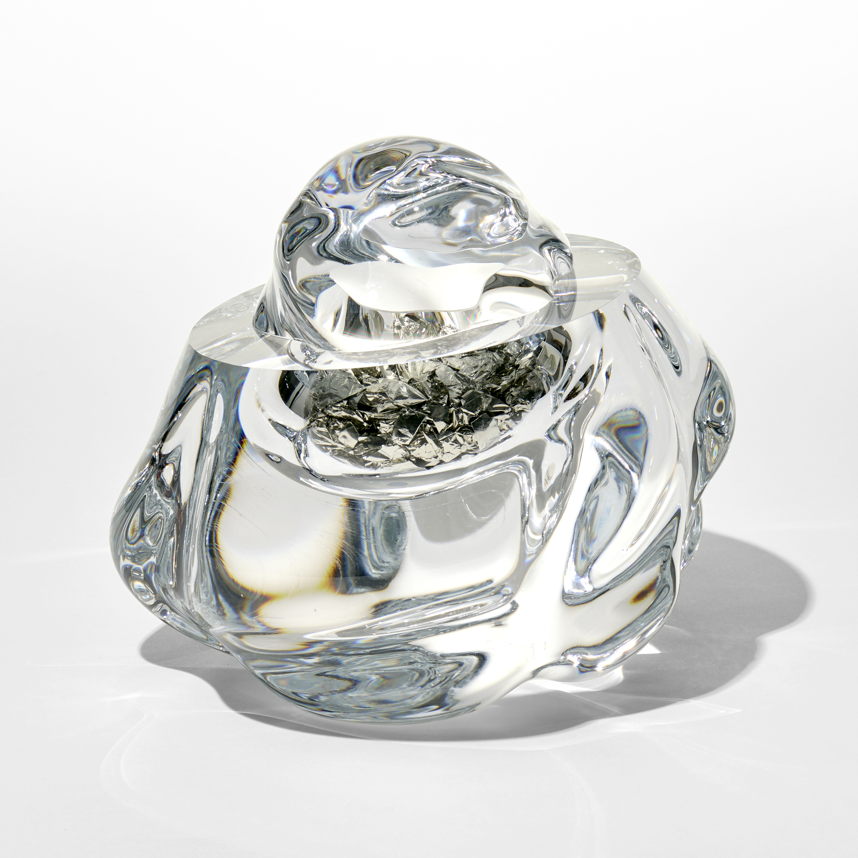 clear amorphous form with the top cut away leaving a flat surface and replaced with a smaller globulous section trapping inside scrunched up sections of tin leaf hand blown and sculpted from glass