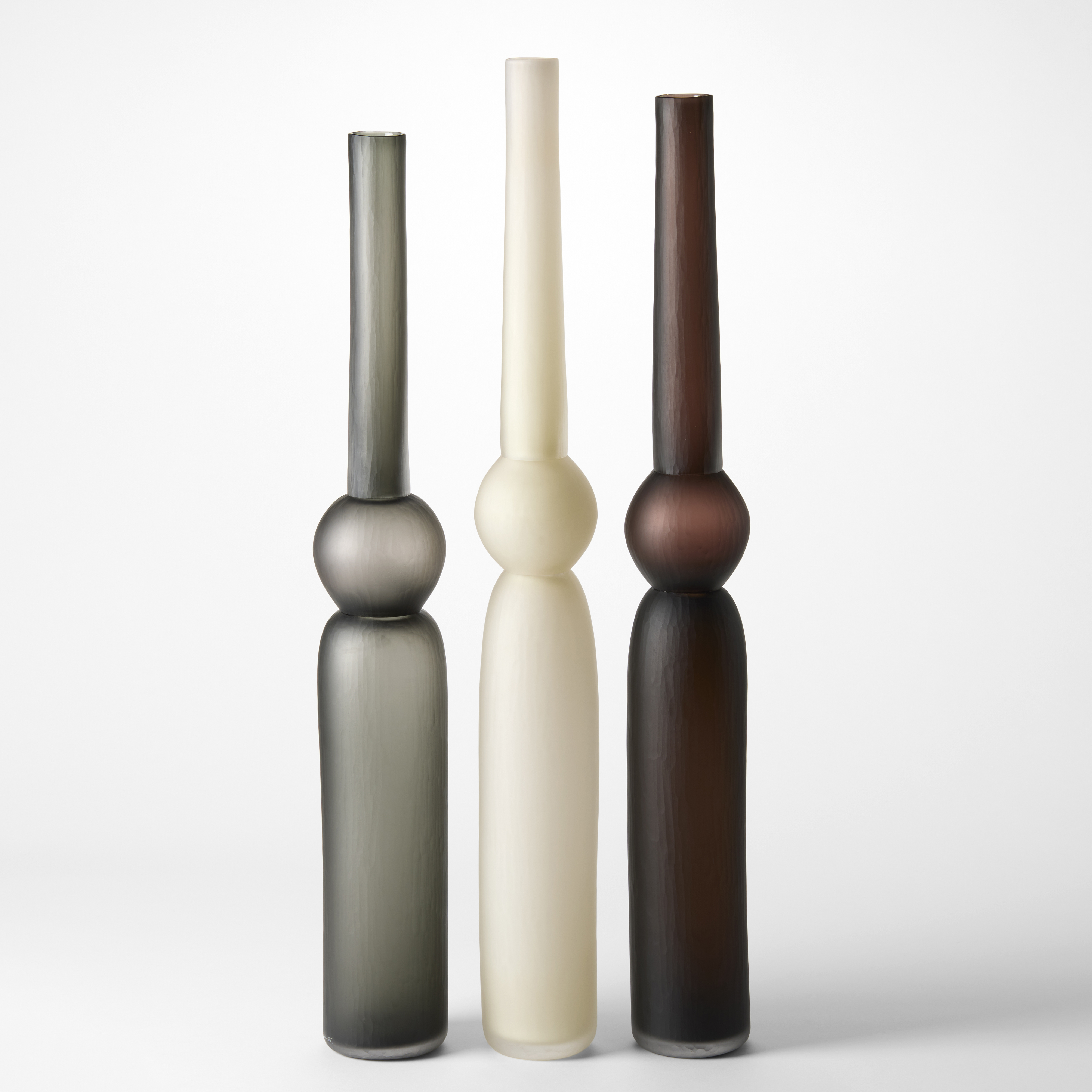 tall column vases created from three stacked forms with two long and tubular and the central one a sphere in grey alabaster and brown each with a matt brushed finish hand blown from glass