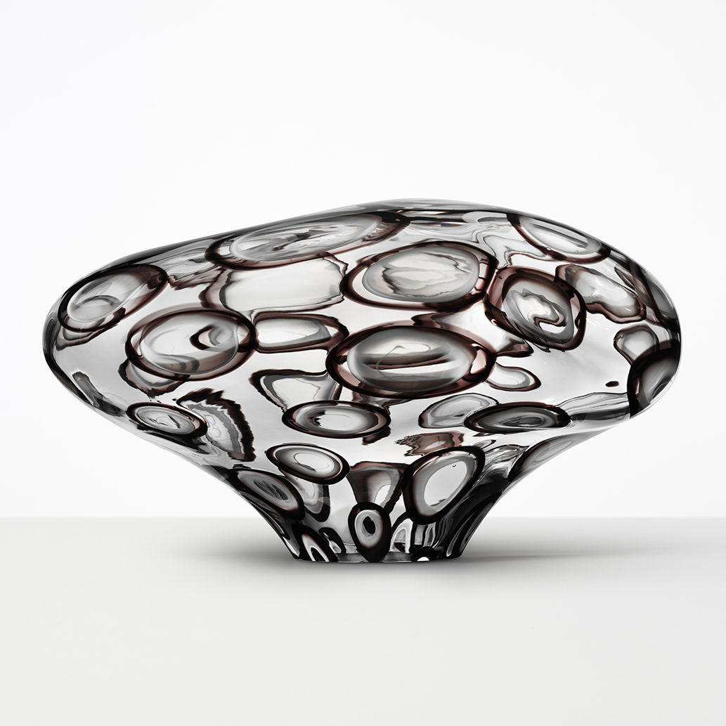 abstract brain-shaped clear glass sculpture with bubble-shaped patterns throughout 