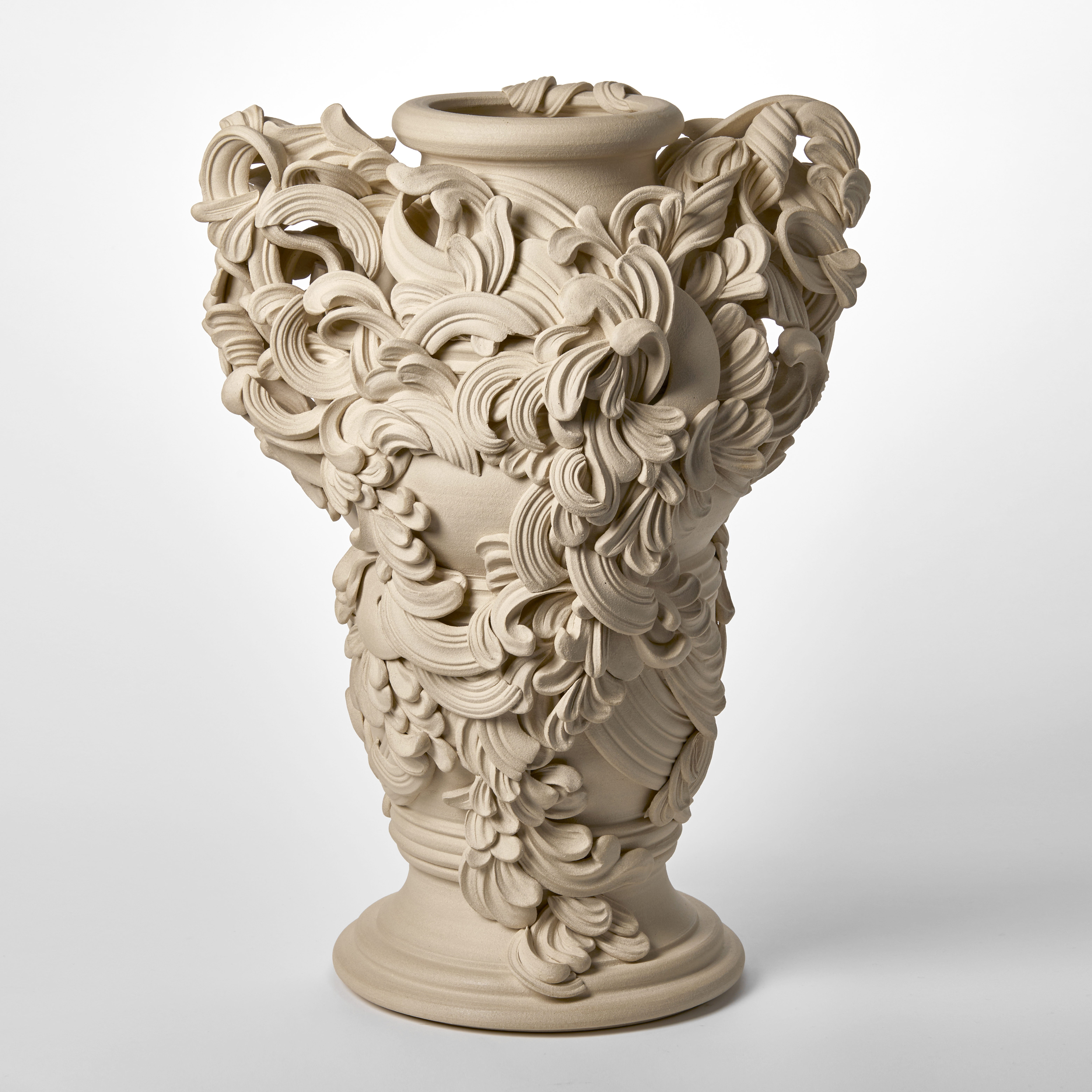 tall architectural ceramic sculptural vessel with handles with the appearance of weather worn sandstone covered in busy adornment of swirls and flourishes hand made from white st thomas clay