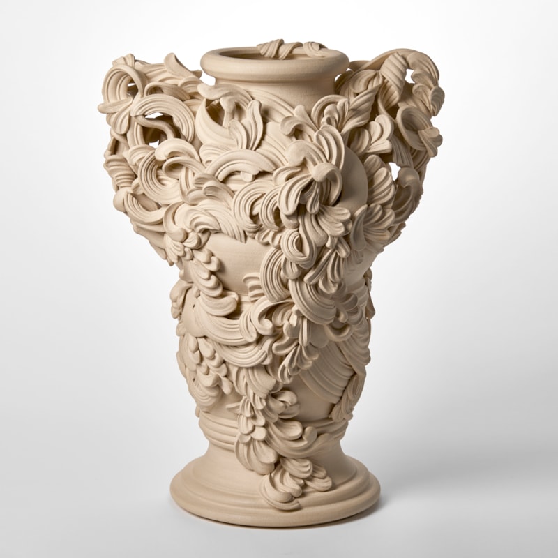 tall architectural ceramic sculptural vessel with handles with the appearance of weather worn sandstone covered in busy adornment of swirls and flourishes hand made from white st thomas clay