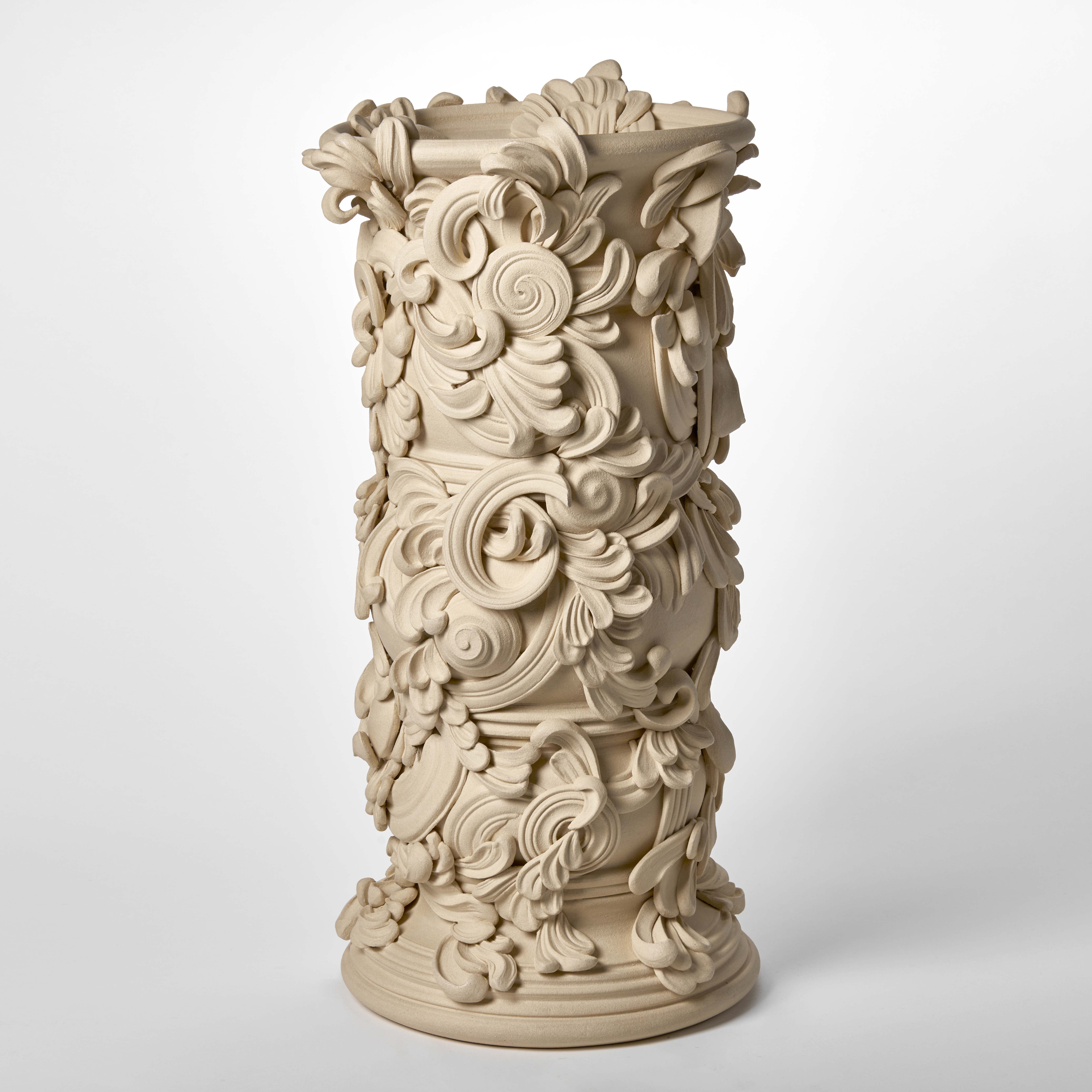 tall architectural vessel with the appearance of weathered sandstone covered in flourishes and swirls hand thrown and sculpted from white st thomas clay