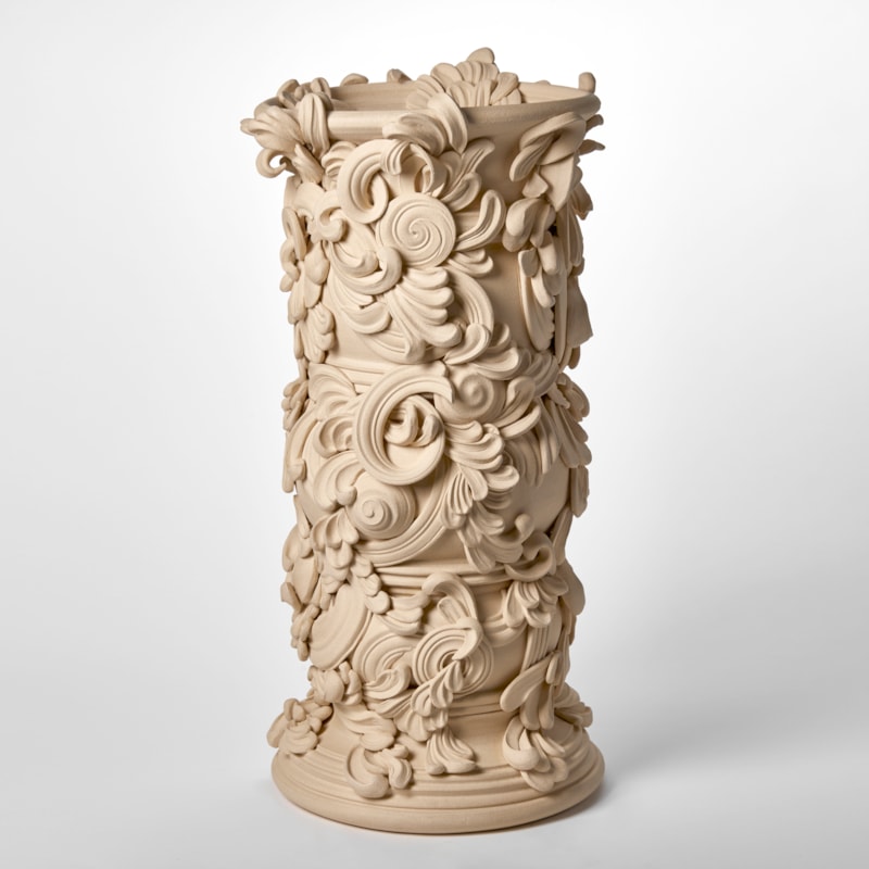 tall architectural vessel with the appearance of weathered sandstone covered in flourishes and swirls hand thrown and sculpted from white st thomas clay