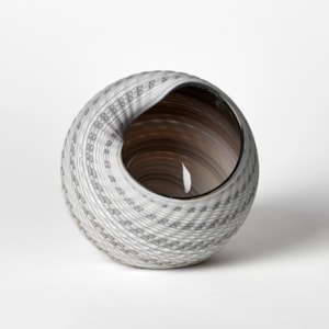 round shell like vessel with large opening glossy interior and matt exterior with incised patterned cut surface and bands of colour in bronze light grey alabaster and white