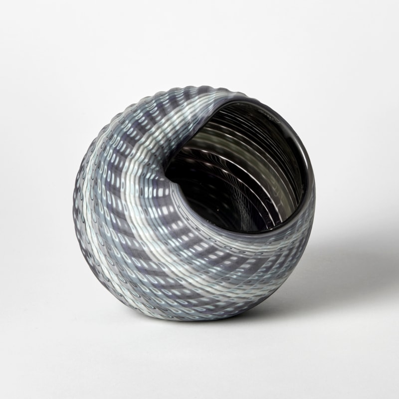 rounded shell like vessel with matt exterior and shiny inside with bands of colours in grey jade blue aqua and white hand made from glass