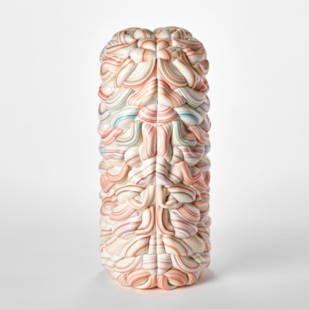 tall undulating and interwoven form in white with rings bands of bright colours in red pinks blues and turquoises with a central seam with each half mirroring each other hand made from parian porcelain