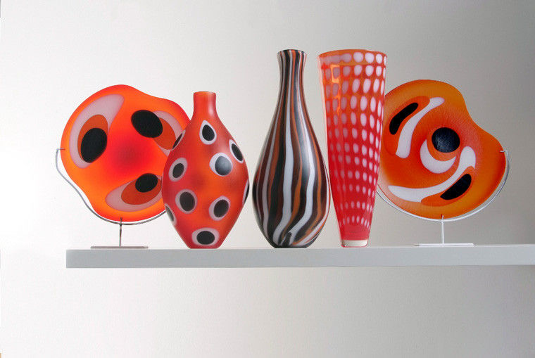 collection of five red art glass sculptures in different shapes with black and white patterns