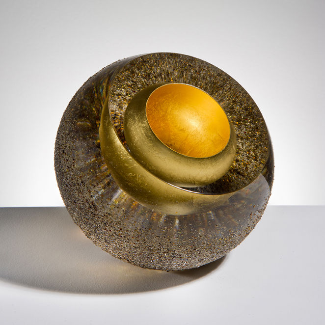 contemporary art glass sculpture of a sphere in earthy colours and layers showing golden core